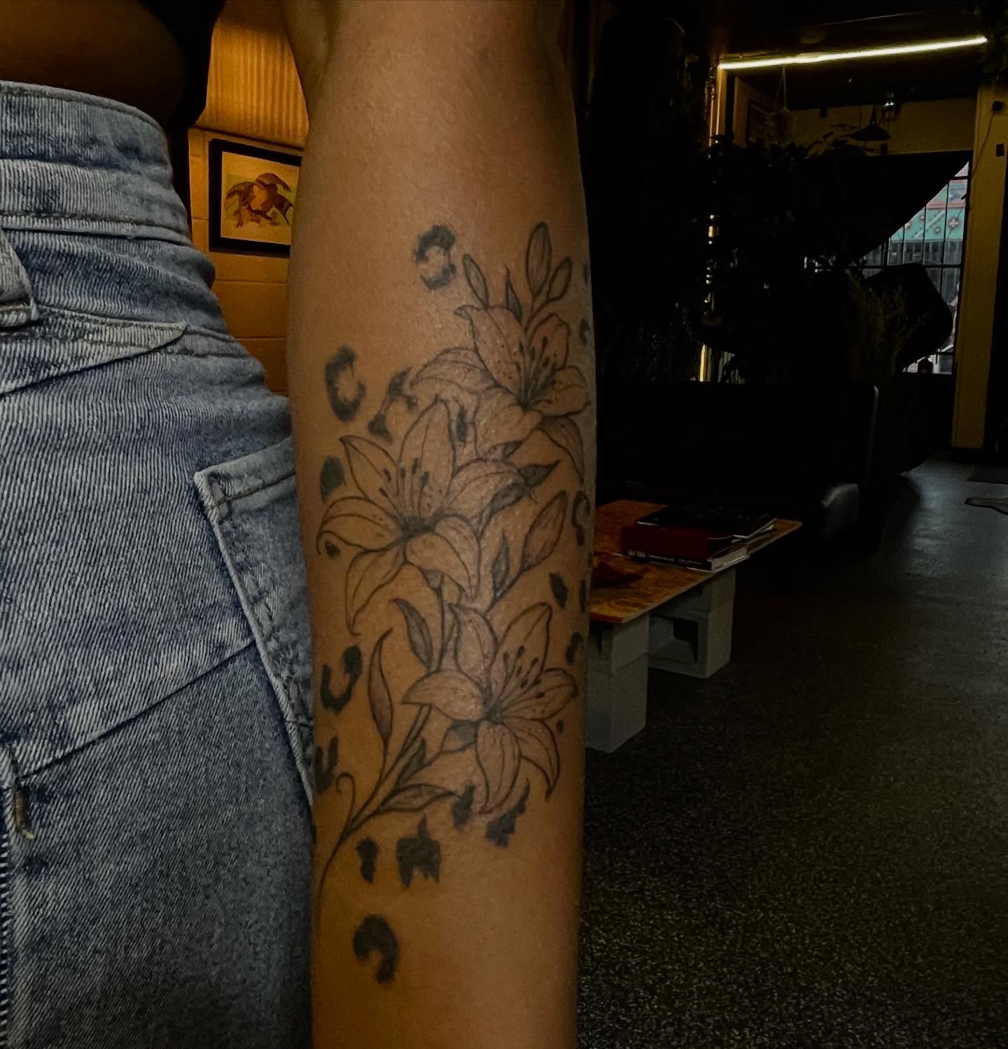 Lilies black and grey tattoo on the forearm by Trinity