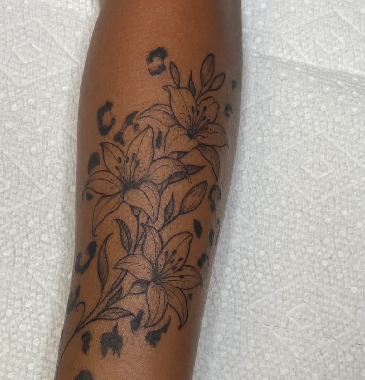 Lilies black and grey tattoo on the forearm by Trinity