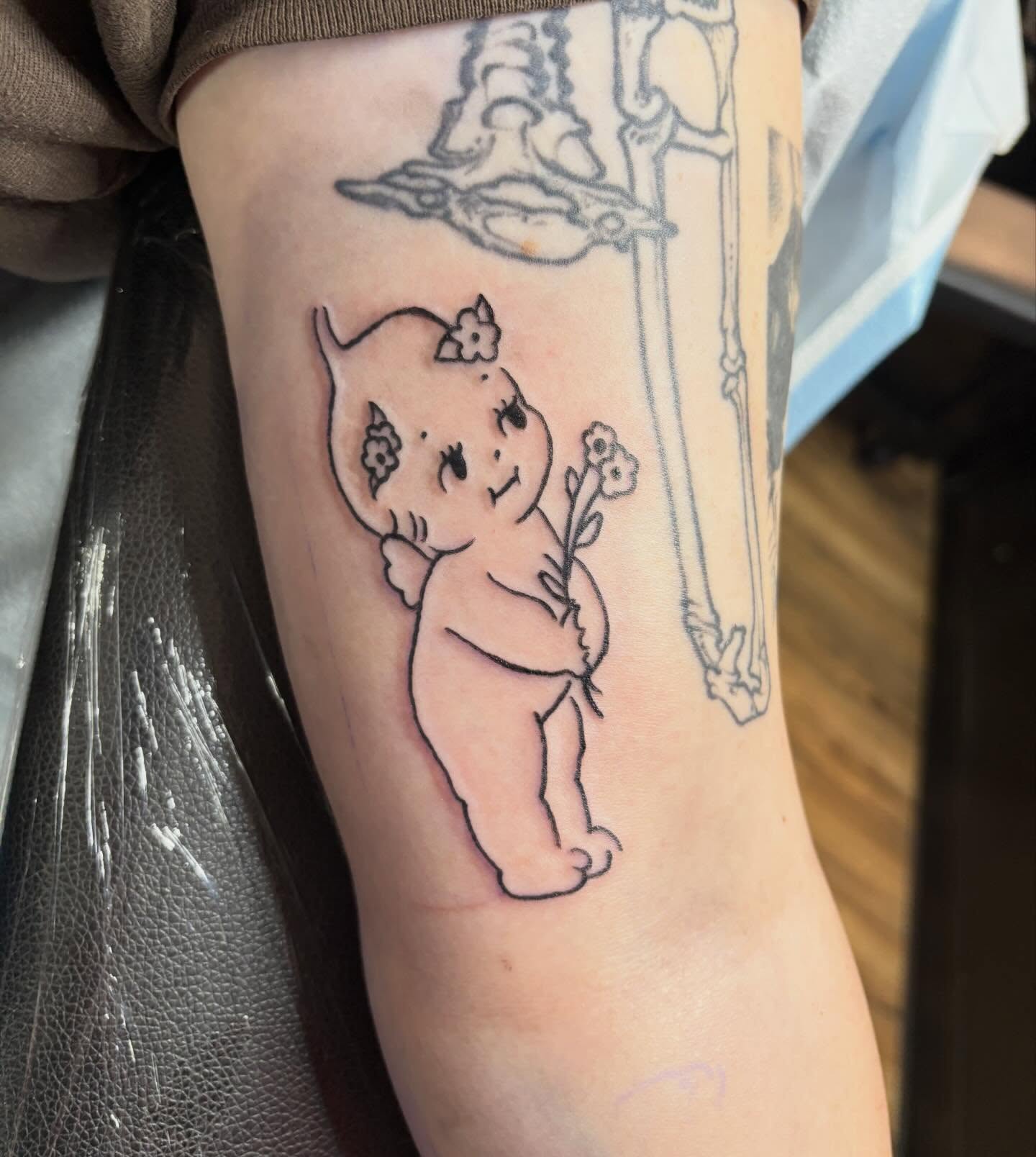 Baby holding flower black and grey tattoo on the forearm by izzy solae