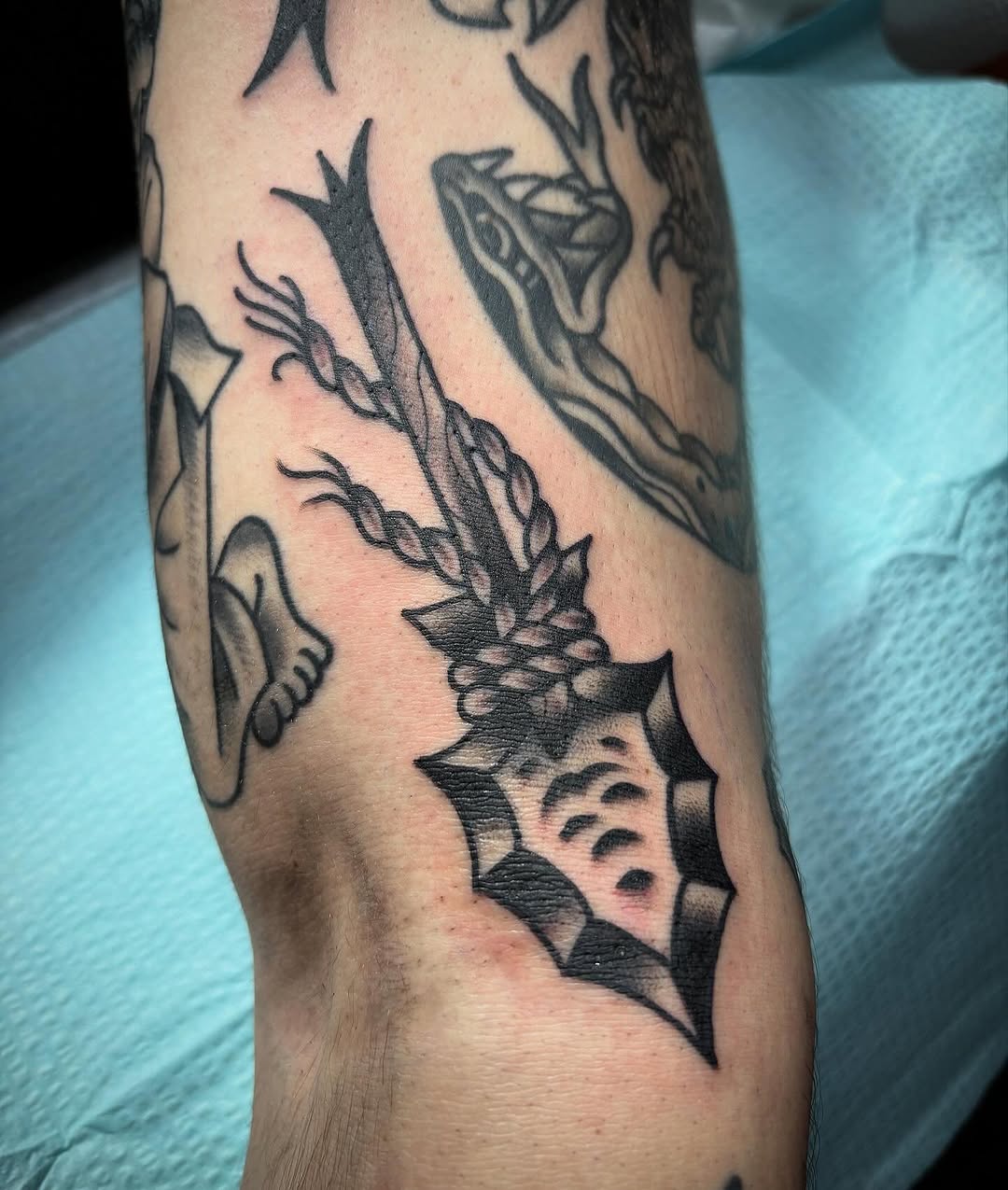 Arrowhead with braided shaft ignorant tattoo on the forearm by Tom Wenzell