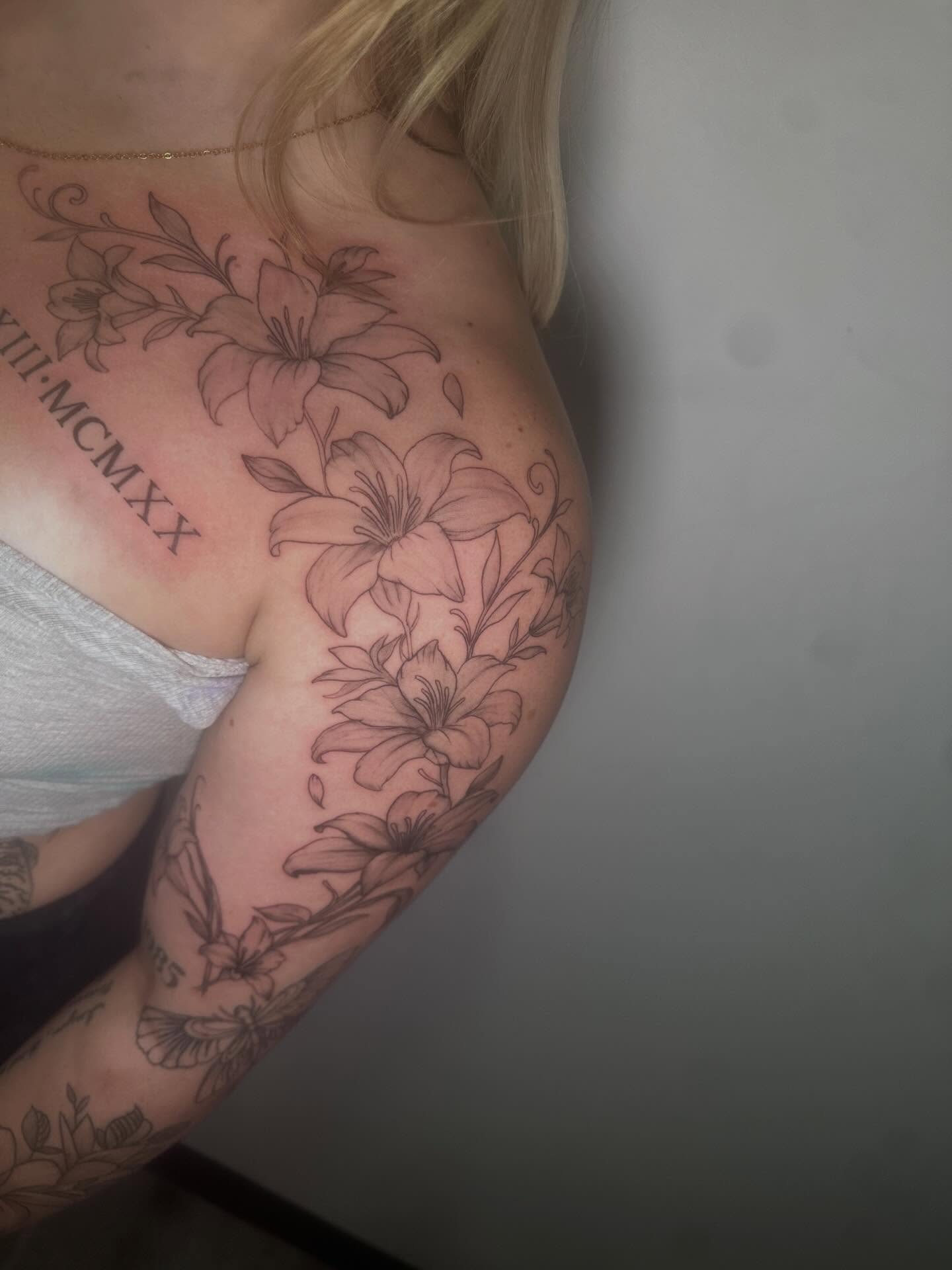 Lilies black and grey tattoo on the upper arm by Javierr Jimenezz
