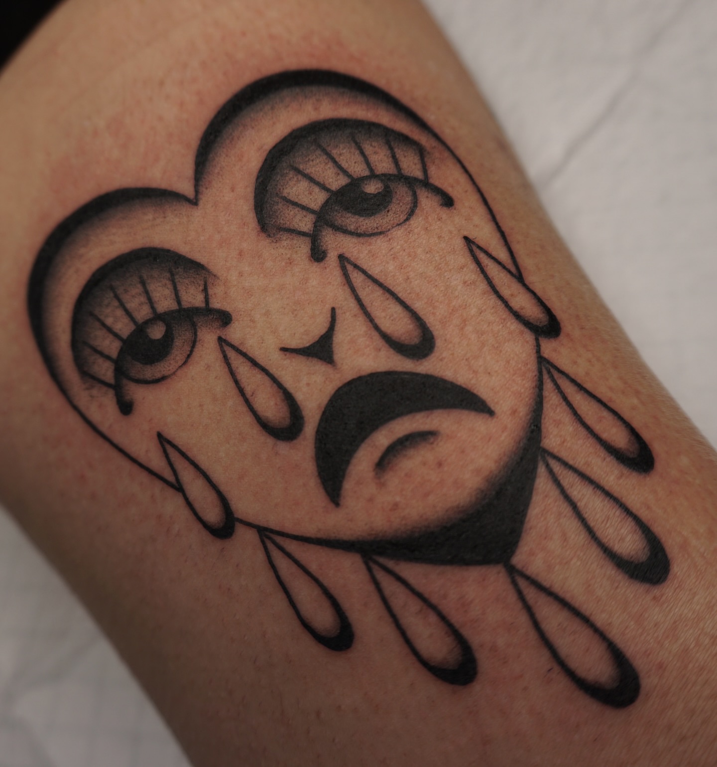 Tearful face black and grey tattoo on the forearm by Sarah Christine Tattoo, Calgary, Alberta