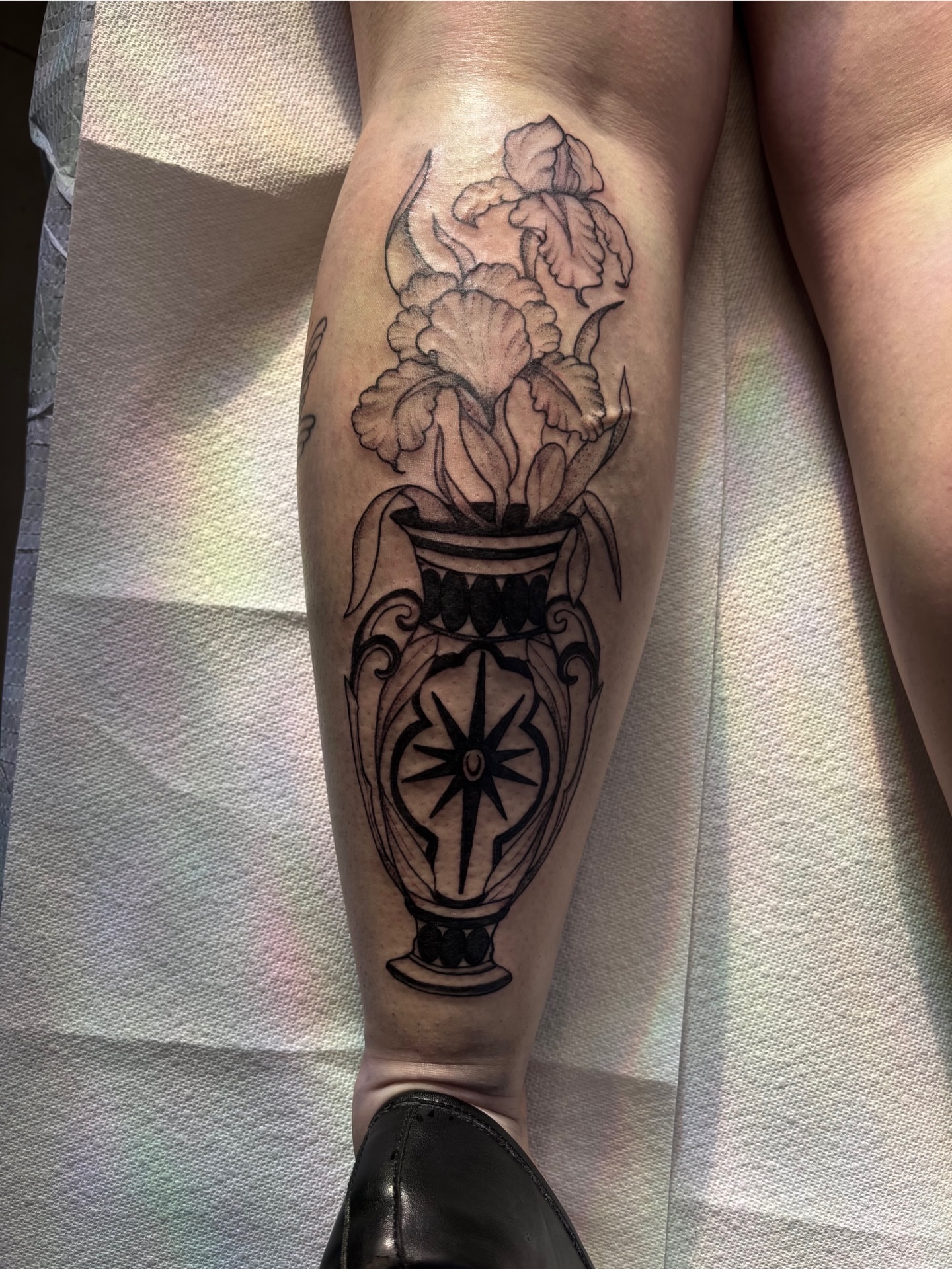 Vase with flowers black and grey tattoo on the calf by Nashville Tattoo Artist