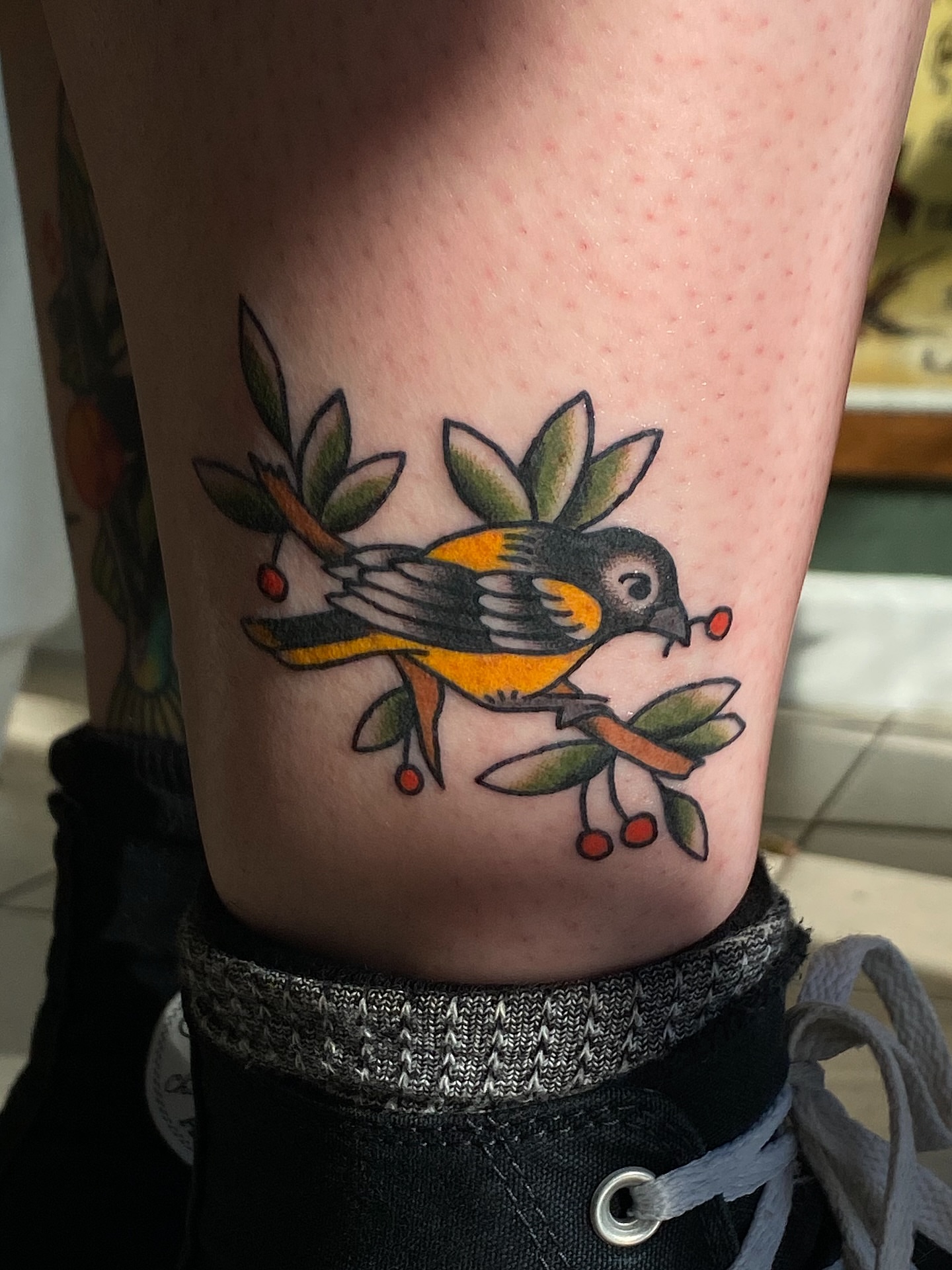 Bird with berries American traditional tattoo on the thigh by Corinne Carter