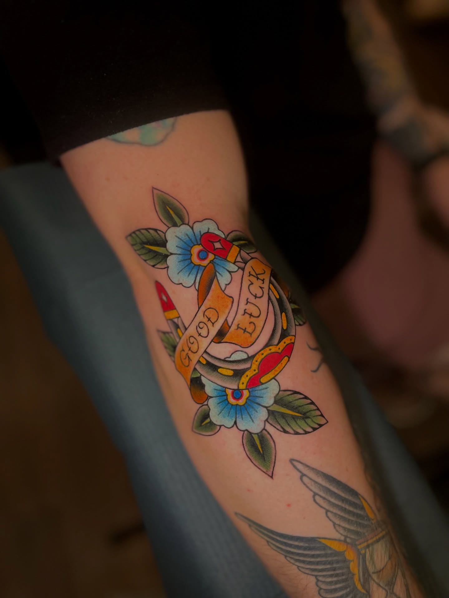 Good luck ribbon American traditional tattoo on the forearm by Ｊｉｍ Ｓｙｌｖｉａ
