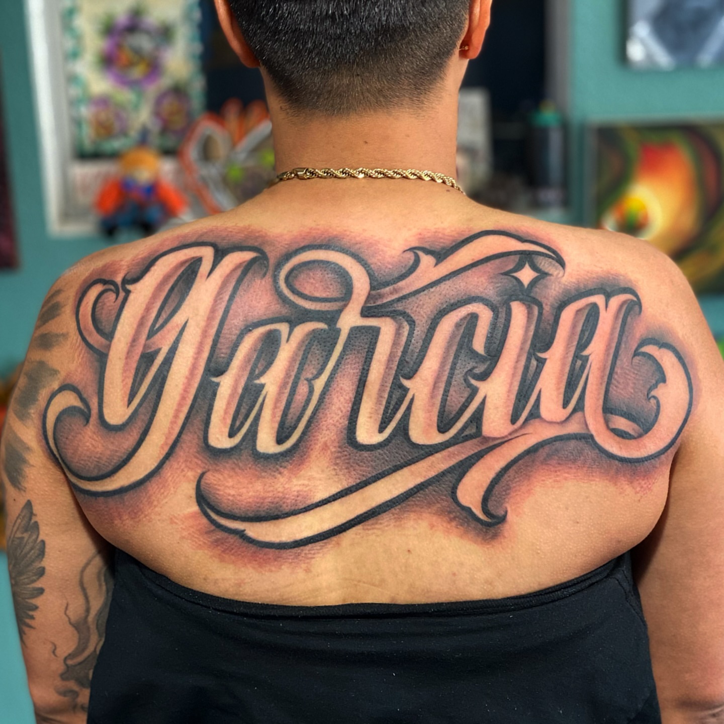 Garcia lettering script tattoo on the back by Lex Miranda