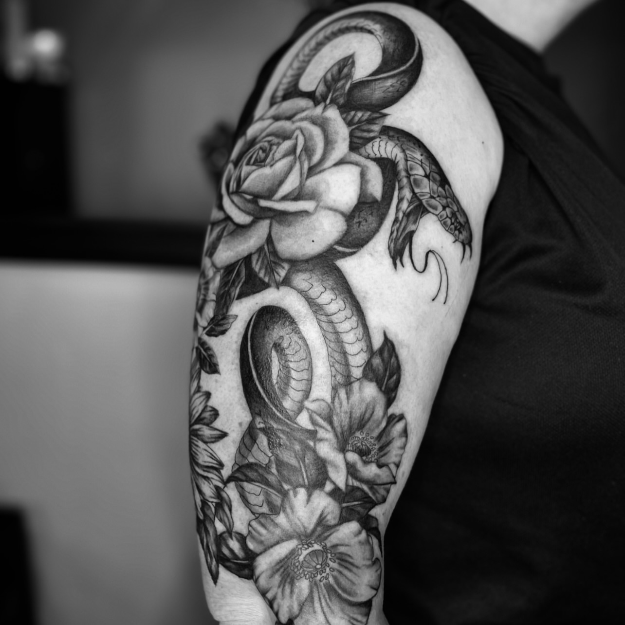 Snake and rose realism tattoo on the upper arm by Sydney Rose