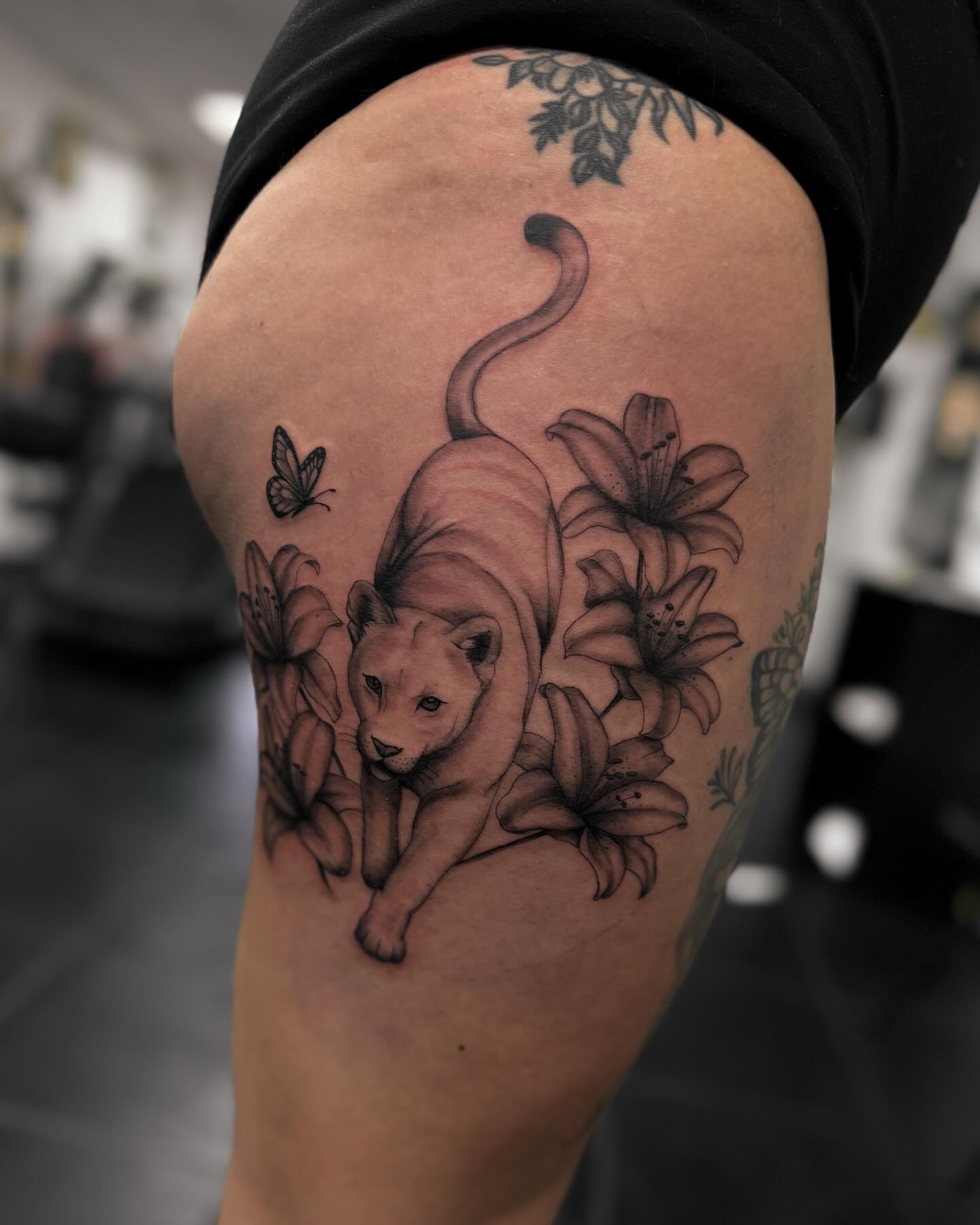 Lion and flowers realism tattoo on the thigh by Rachel