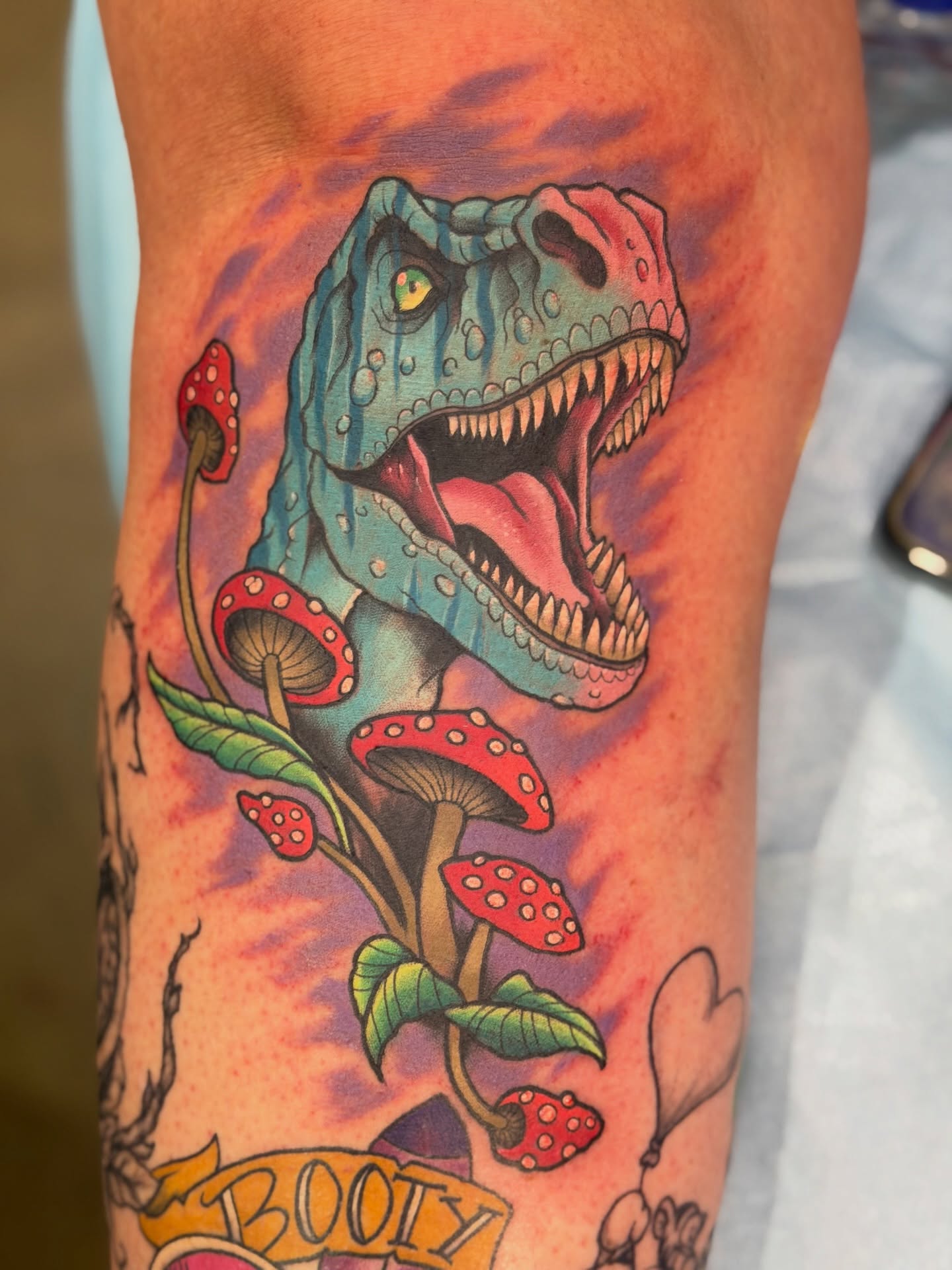 T-Rex and mushrooms new school tattoo on the forearm by James Mullin