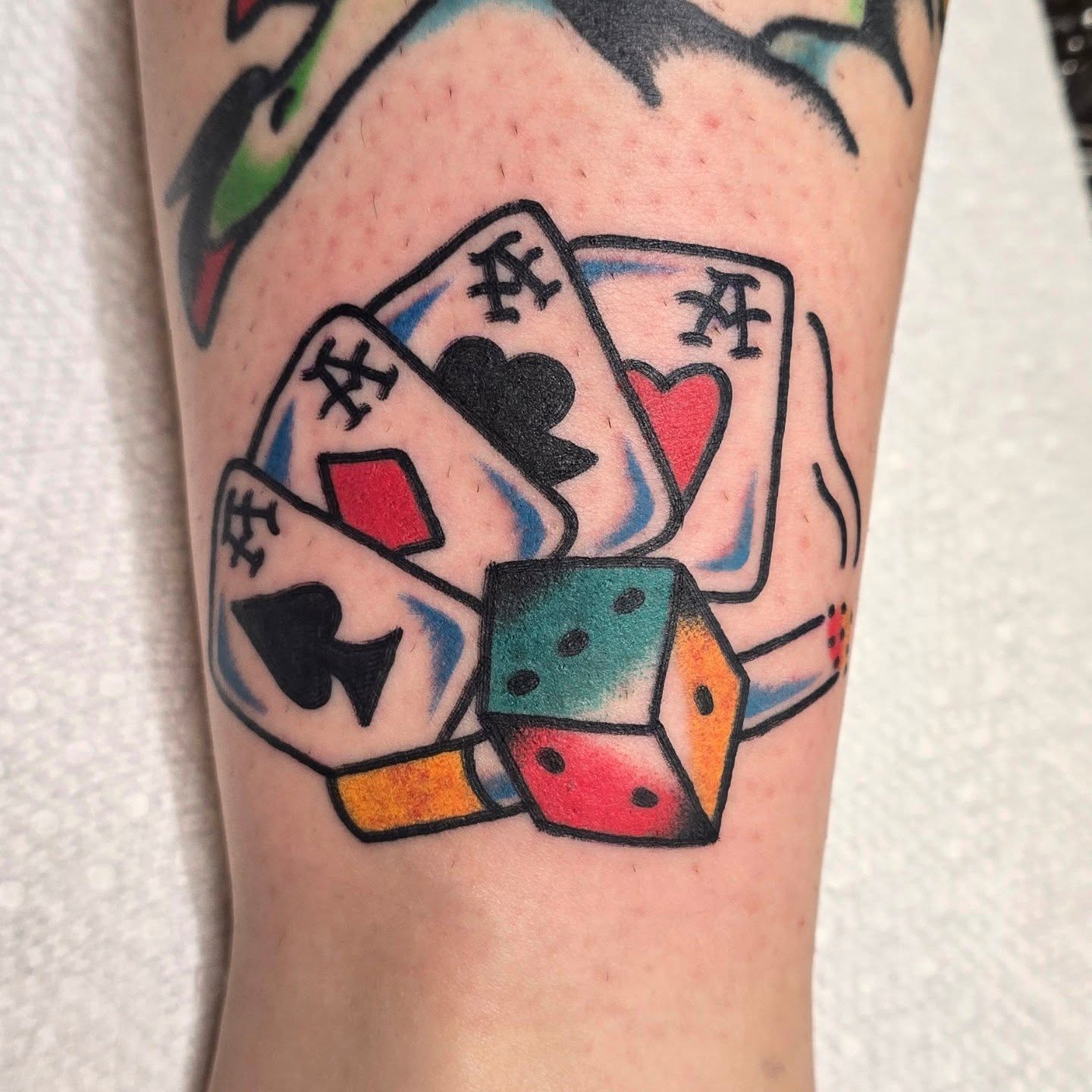 Playing cards and dice American traditional tattoo on the forearm by A. Teixeira, Los Angeles, California