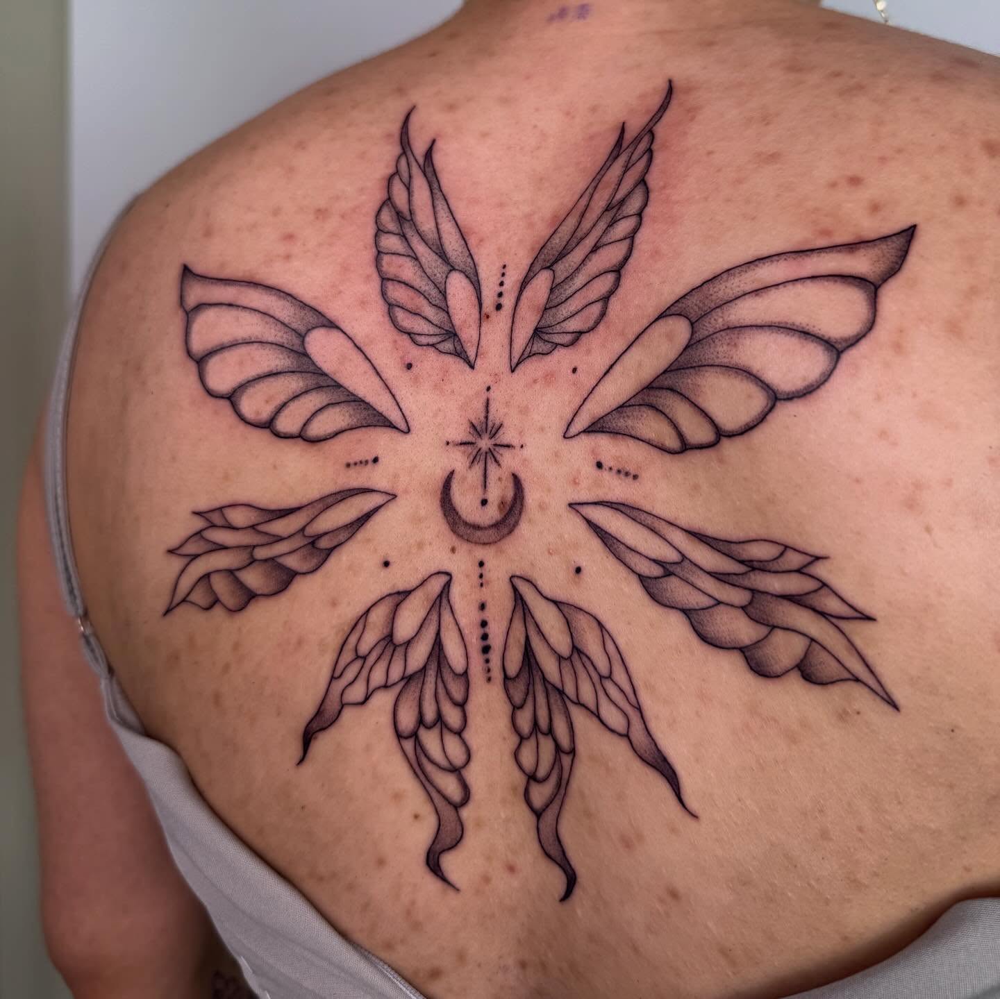 Wings and moon dotwork tattoo on the back by Nika