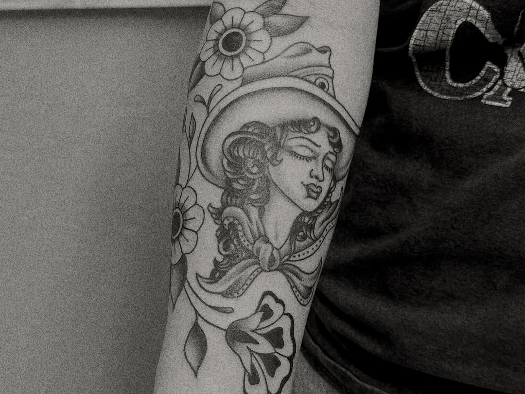 Cowgirl portrait with flowers realism tattoo on the forearm by Matthew Ulrich