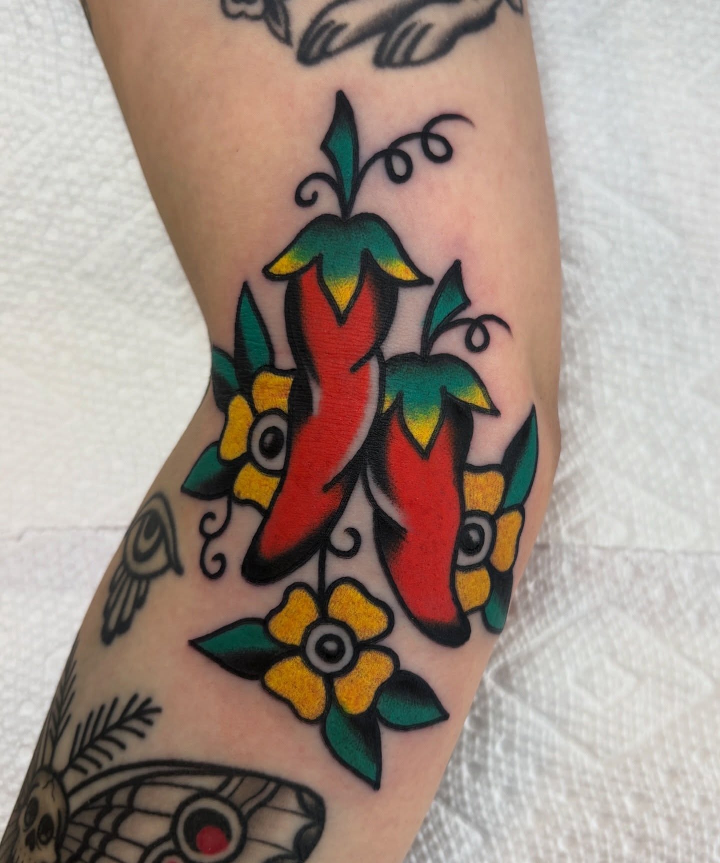 Chili peppers and flowers American traditional tattoo on the forearm by Traditional Tattooing