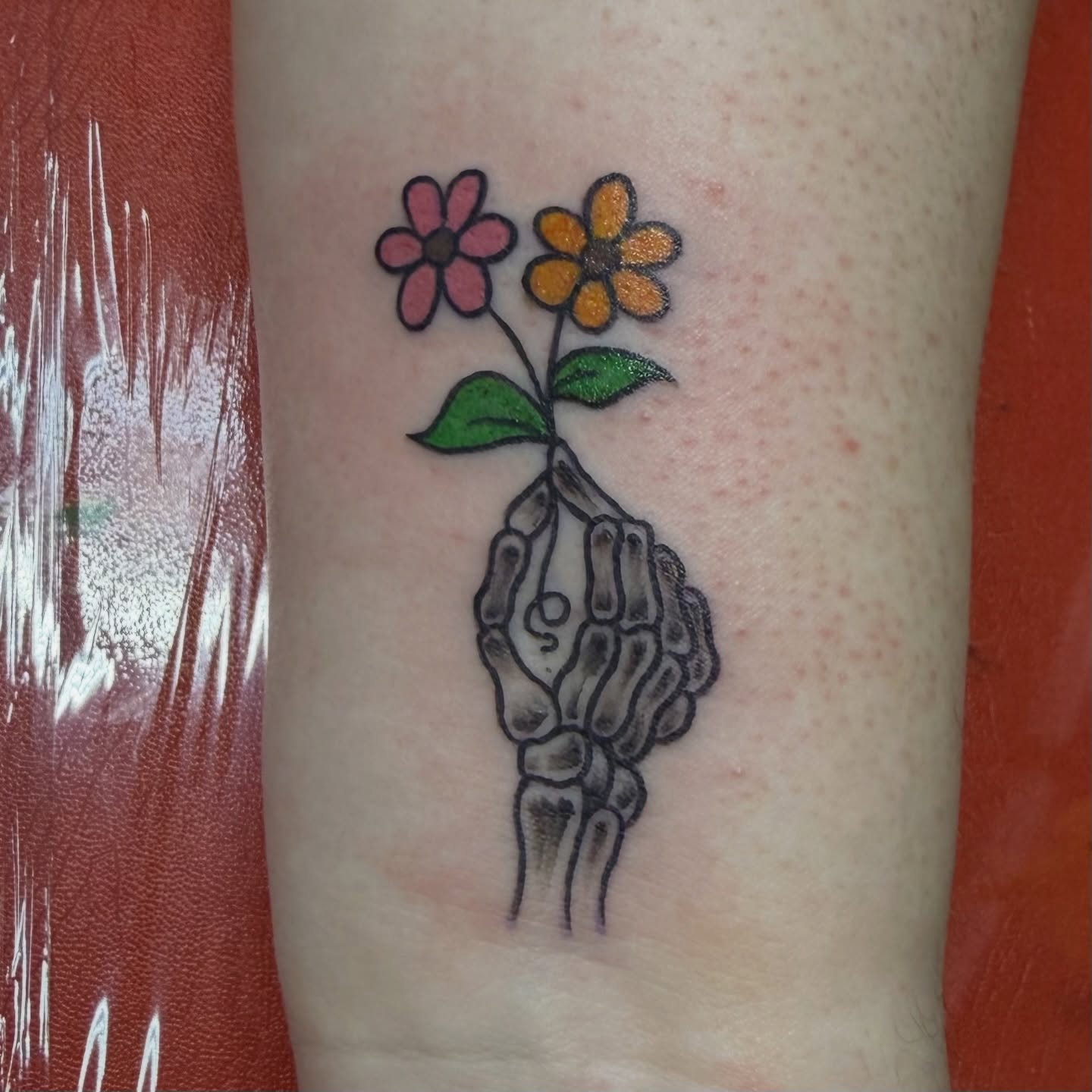 Flower and skeleton hand dotwork tattoo on the forearm by Squid