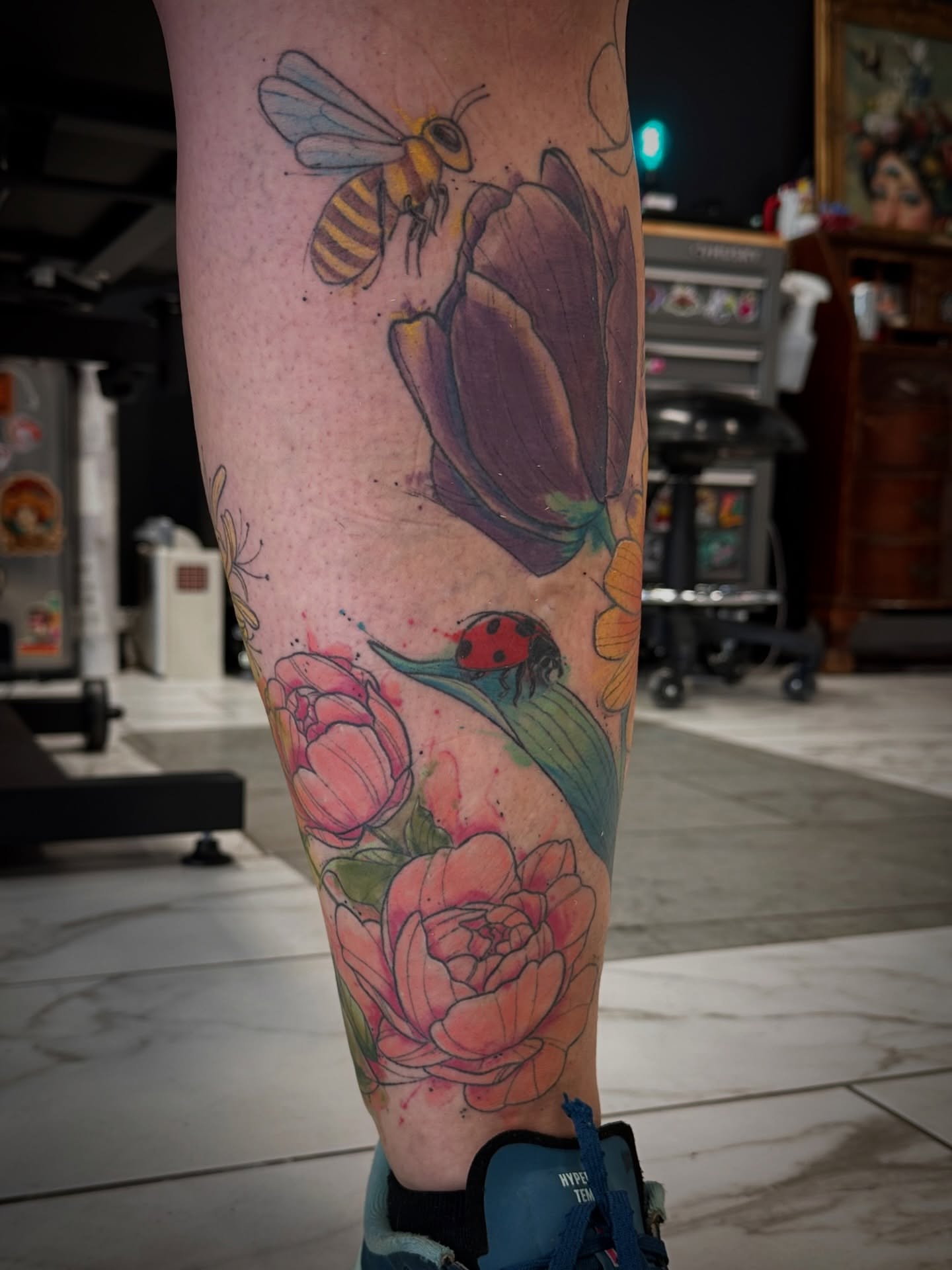 Flowers and insects watercolor tattoo on the calf by Chris Gray