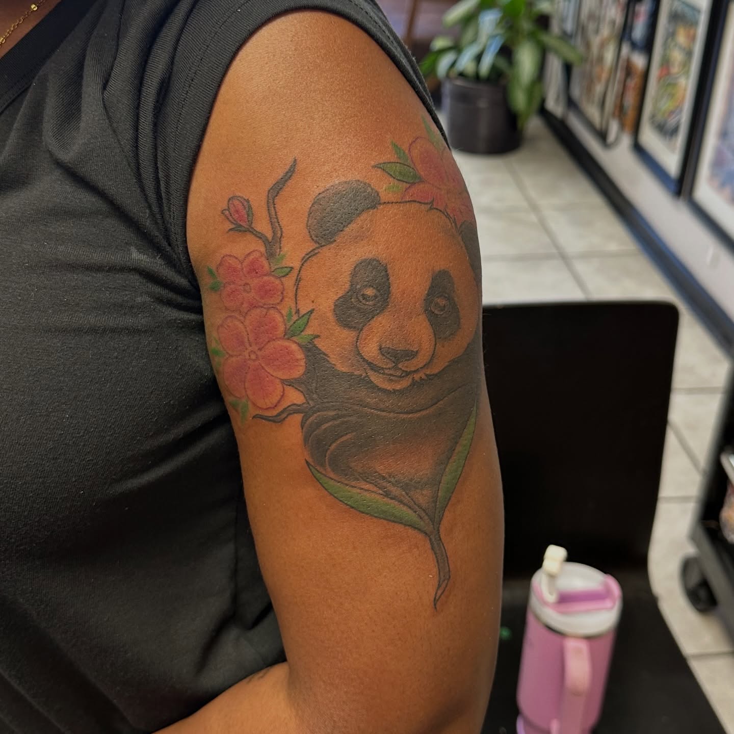 Panda and flowers realism tattoo on the upper arm by Mia Layne 🤎