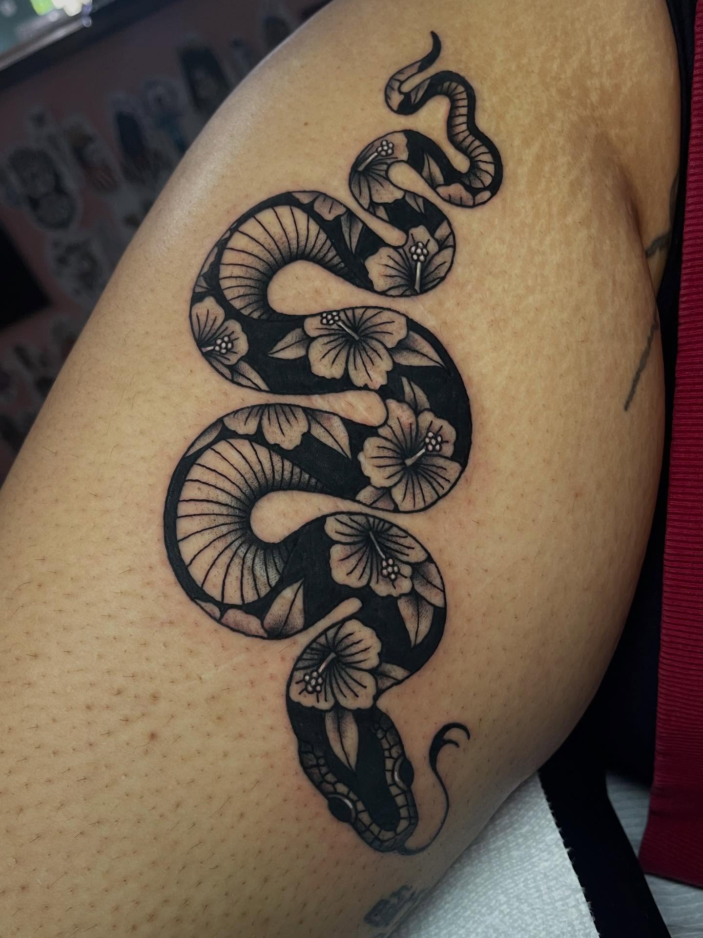Snake and flowers ornamental tattoo on the thigh by Marqui Watling