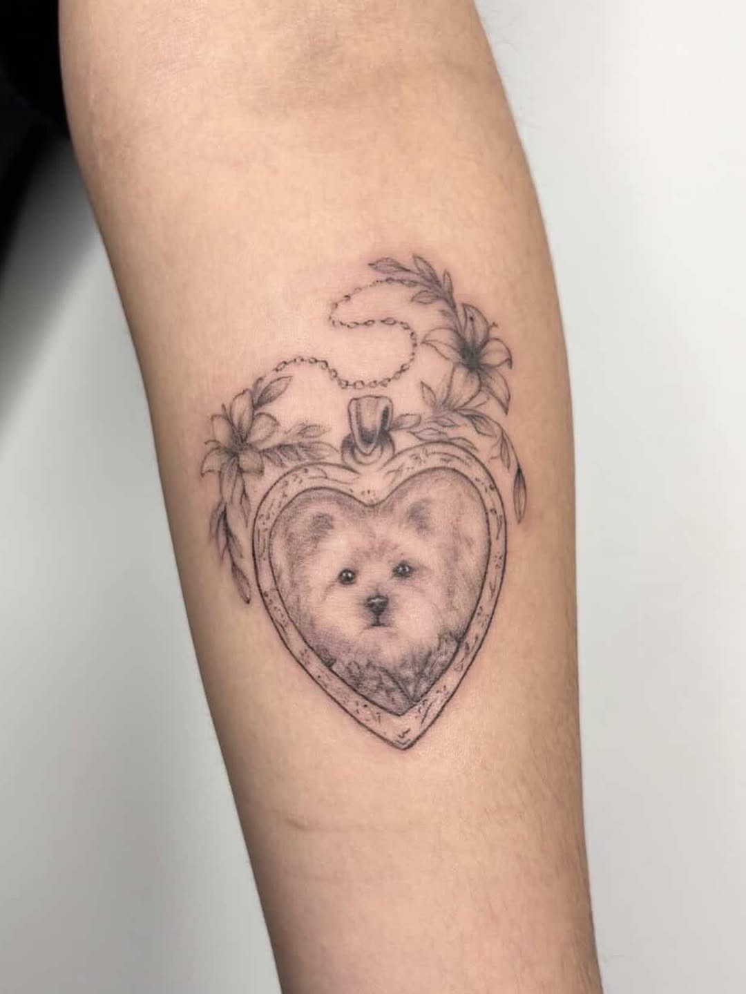 Dog in locket realism tattoo on the forearm by Jinz