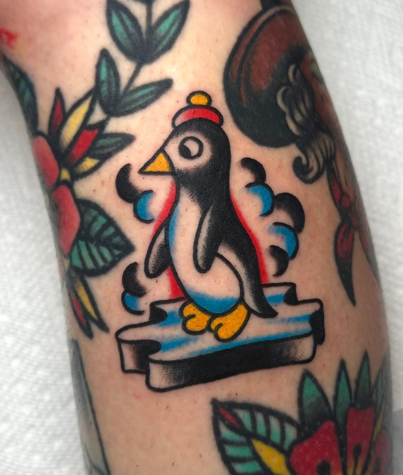 Penguin American traditional tattoo on the forearm by Zahra Niedermann