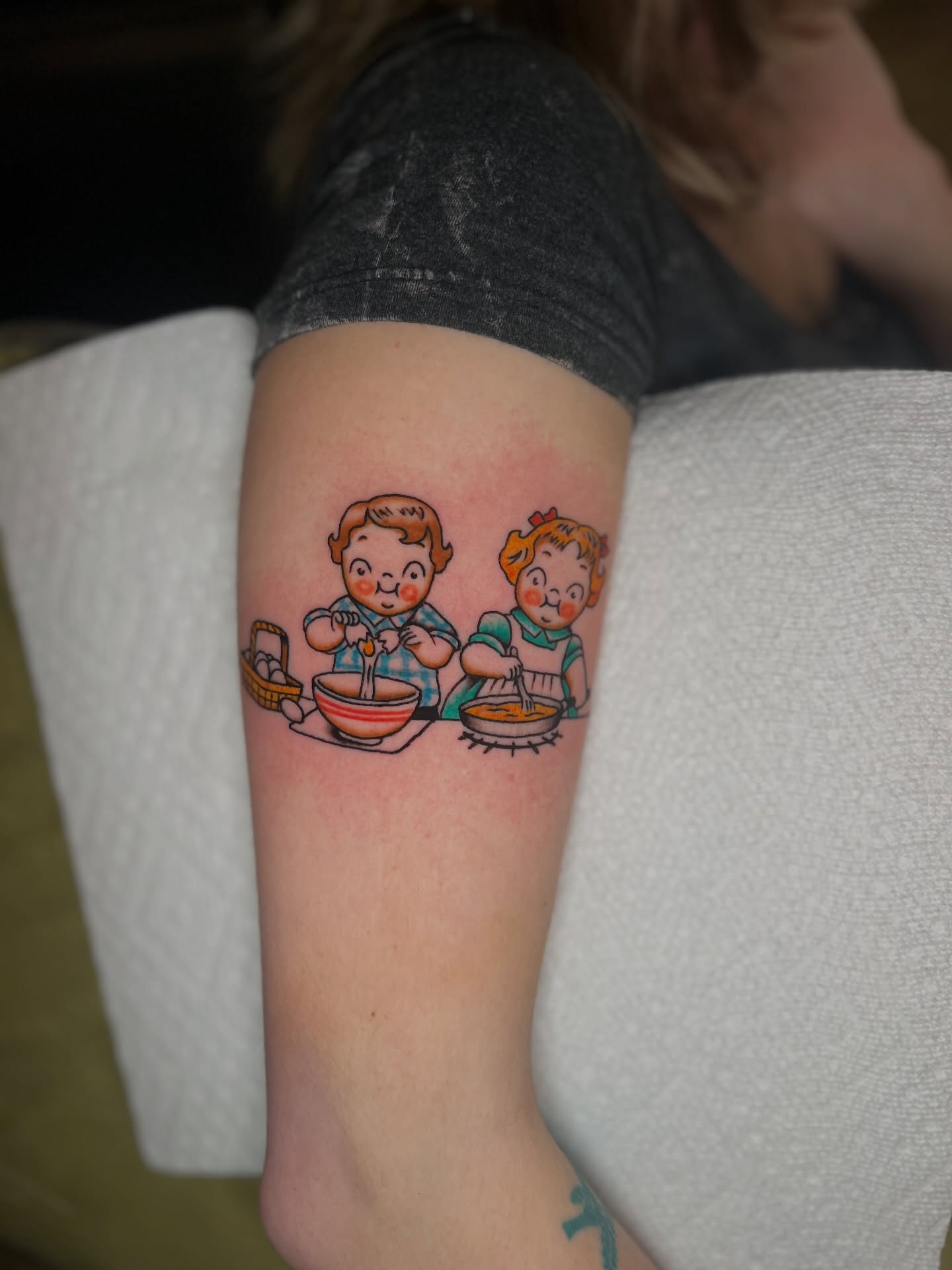 Cooking children illustrative tattoo on the forearm by Andrew Storm
