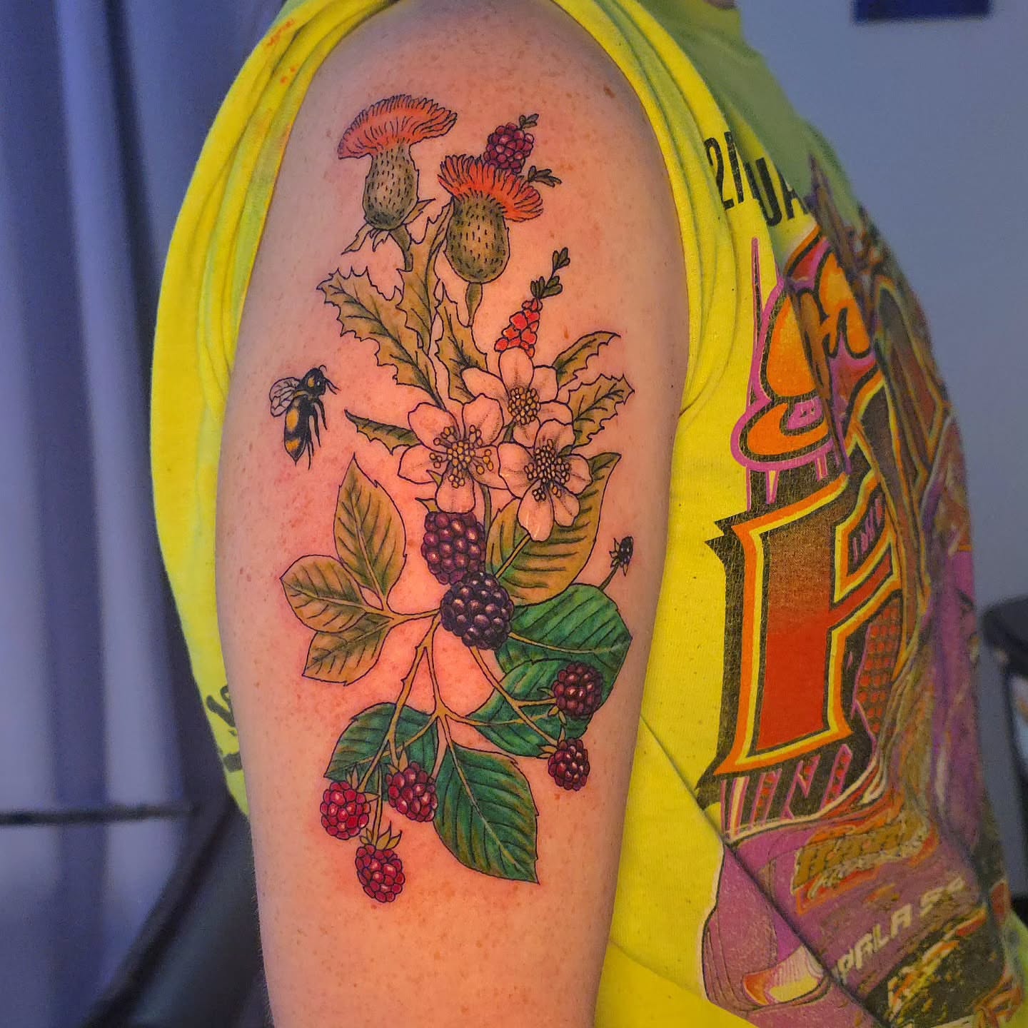 Flower and berries illustrative tattoo on the upper arm by Karley Michelle Moody