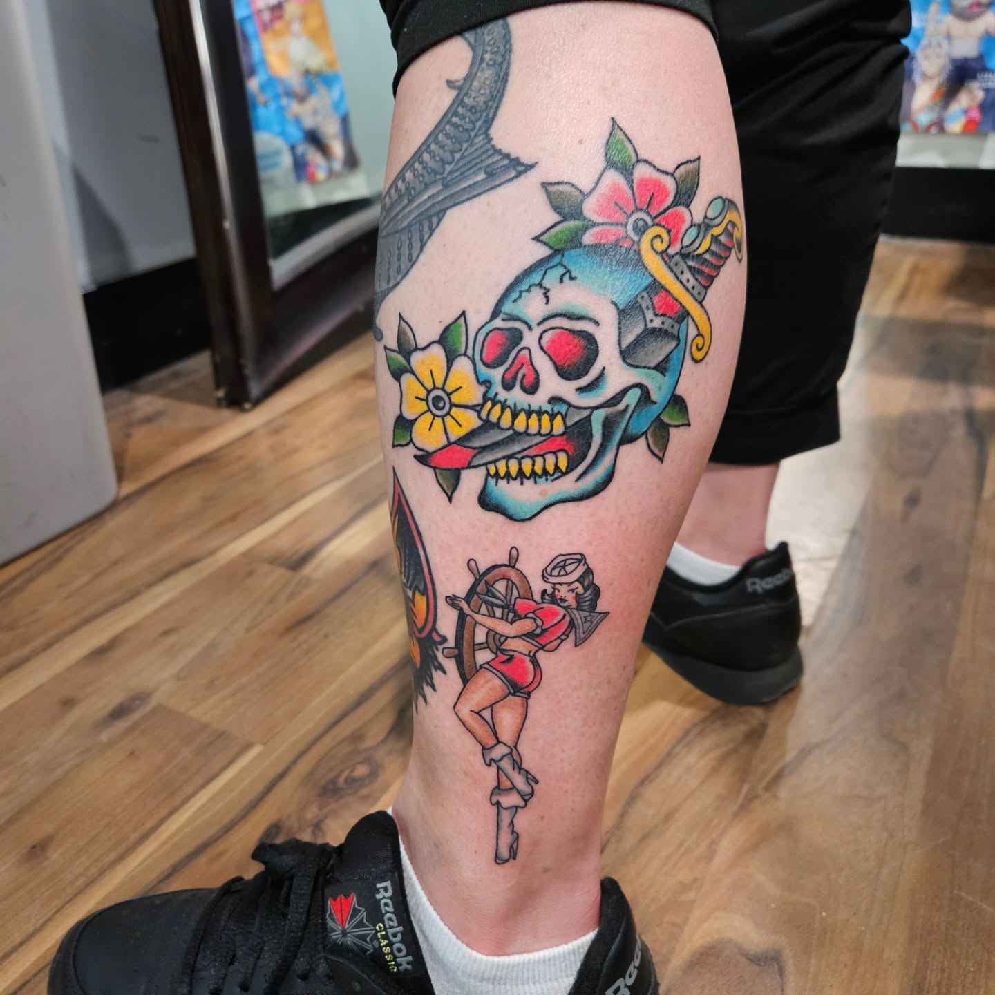 Pin-up girl with skull American traditional tattoo on the calf by Danny
