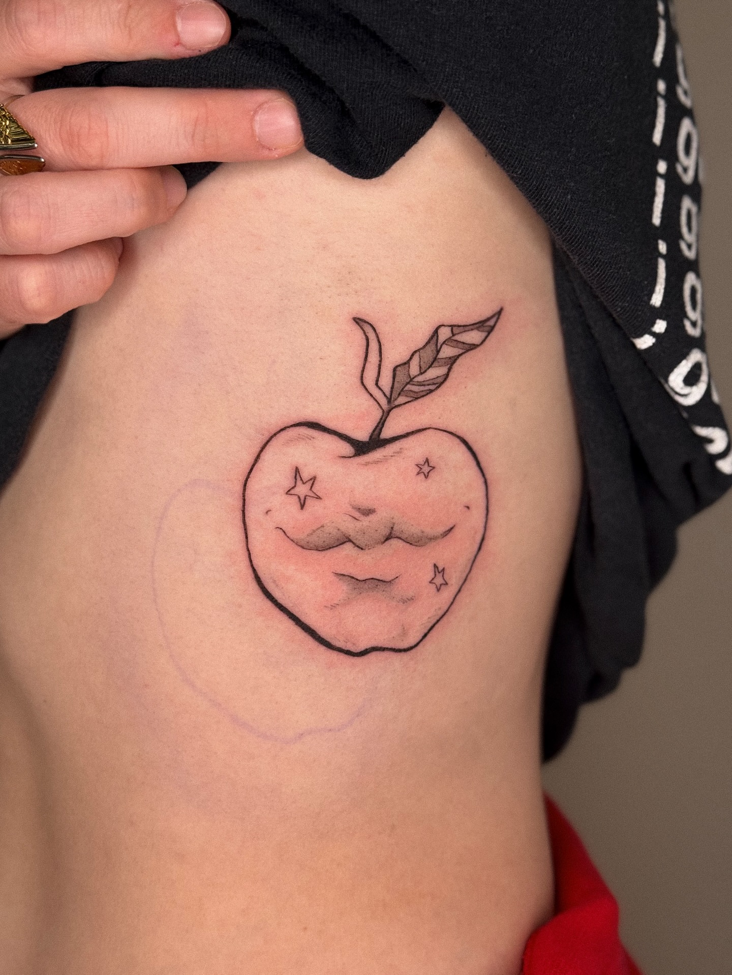 Apple with mustache geometric tattoo on the ribs by madison
