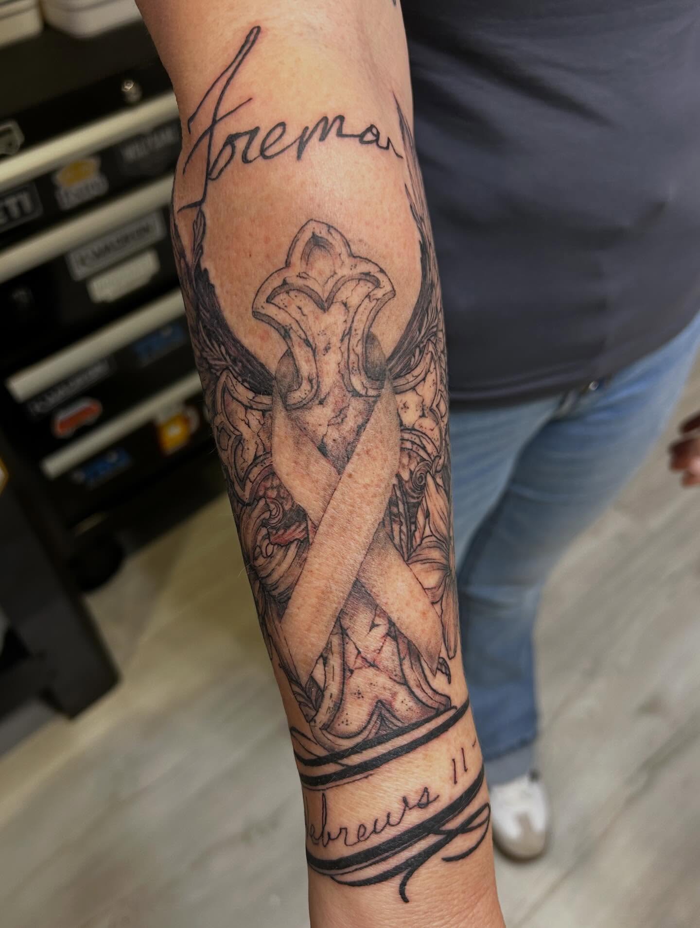 Cross and ribbon black and grey tattoo on the forearm by Jbtattoo Artistry