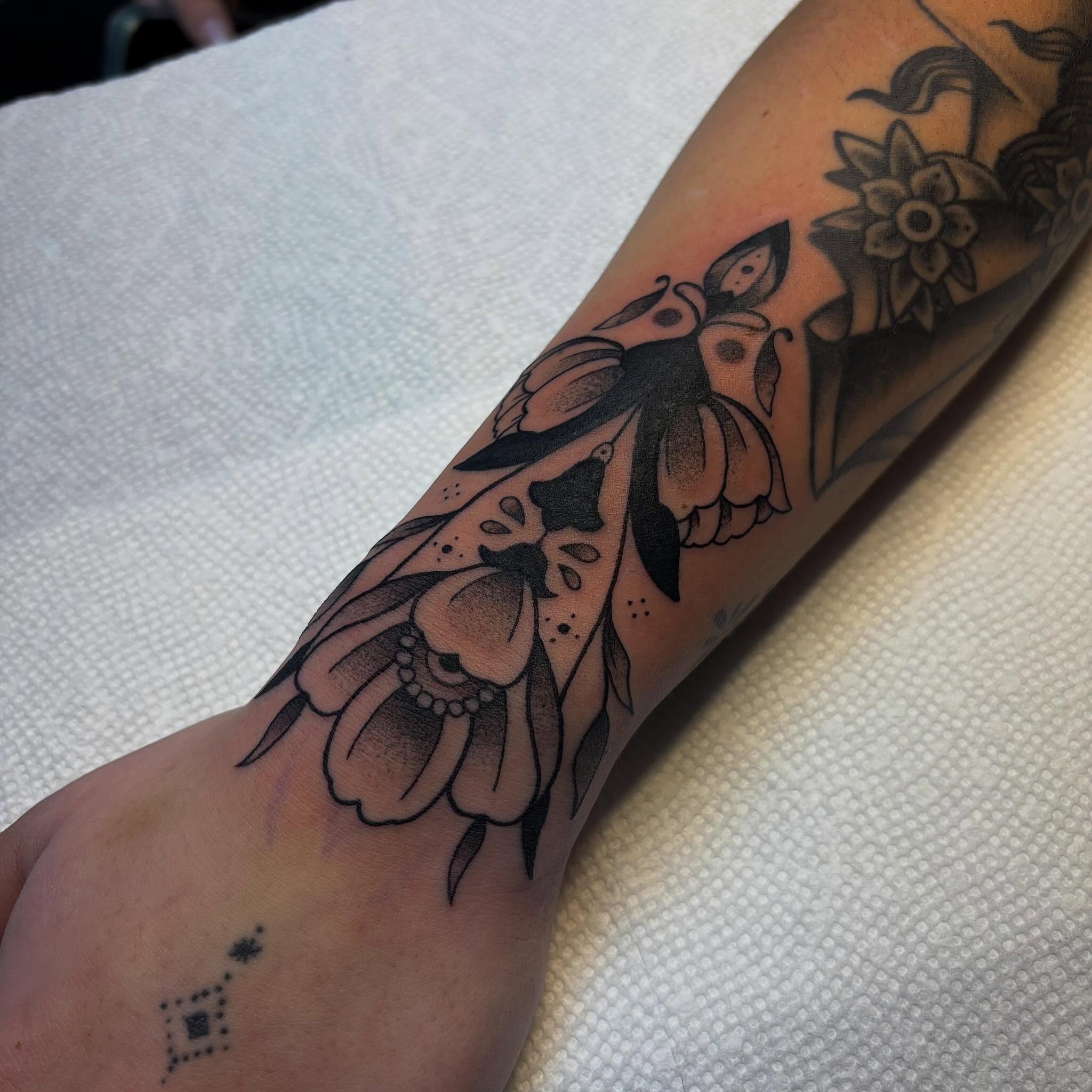Floral bird American traditional tattoo on the forearm by Dyllan Shipley