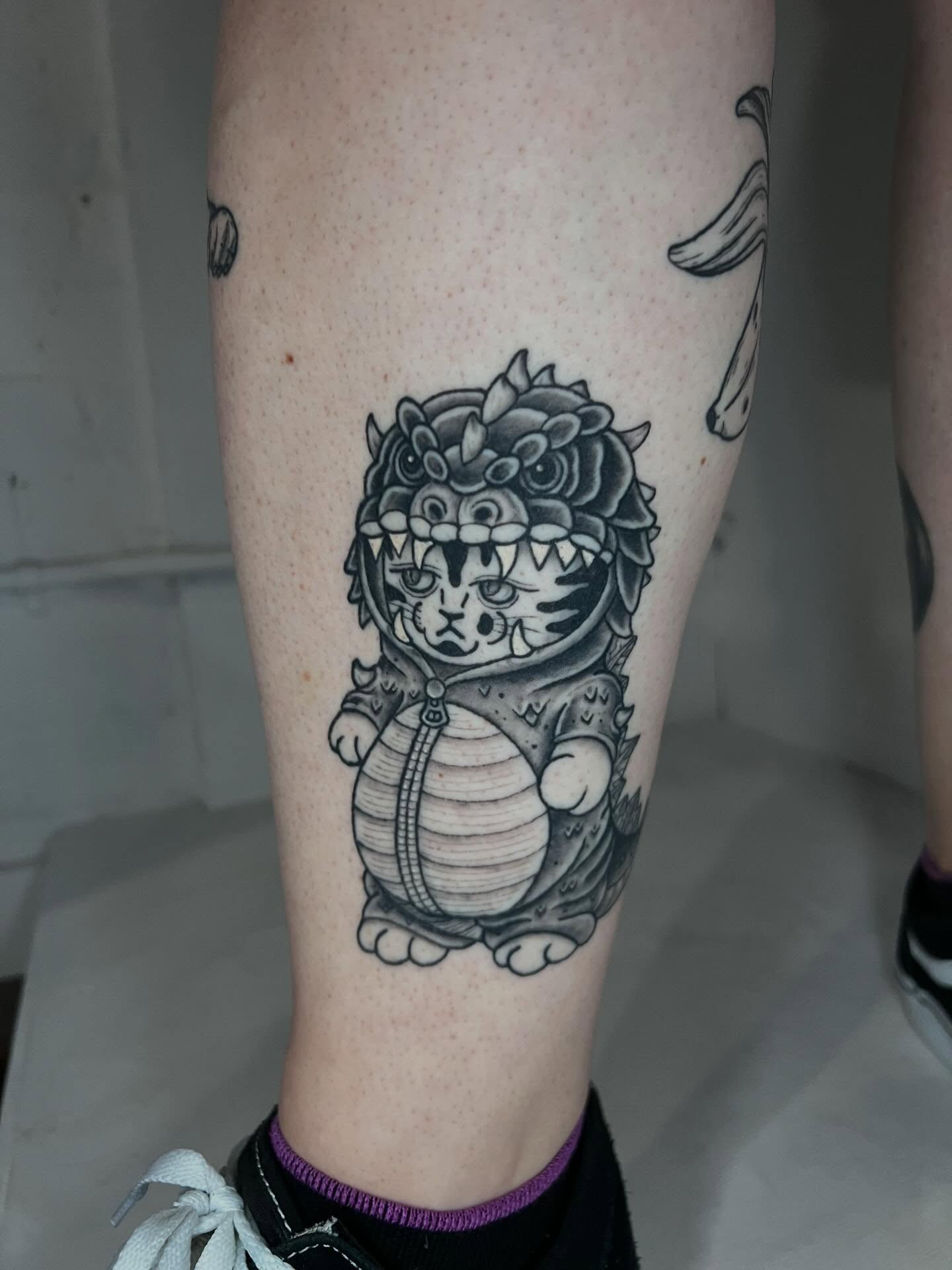 Cat in armor black and grey tattoo on the calf by Eoghann McGregor