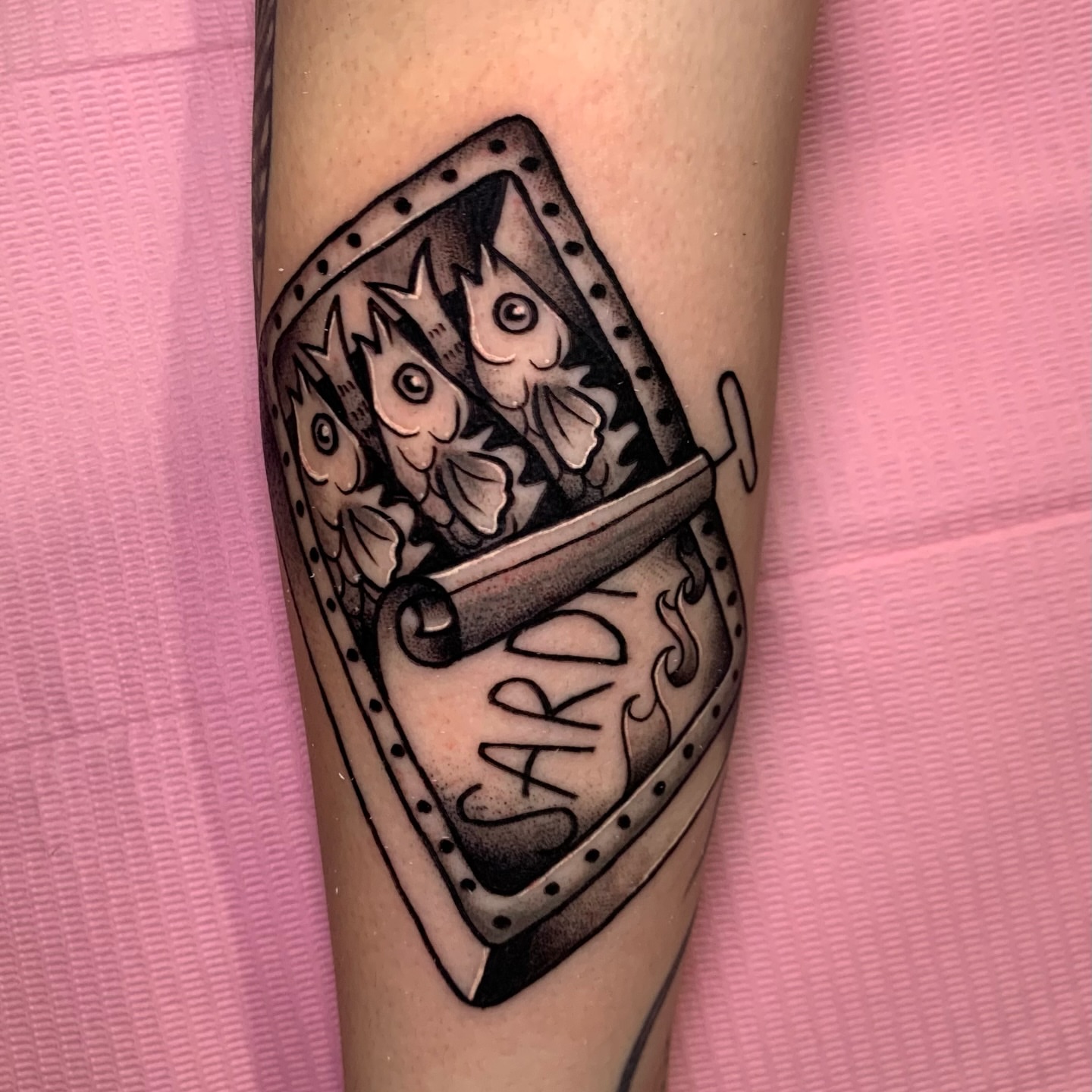 Shield with fish black and grey tattoo on the forearm by Aubrianna Grisez