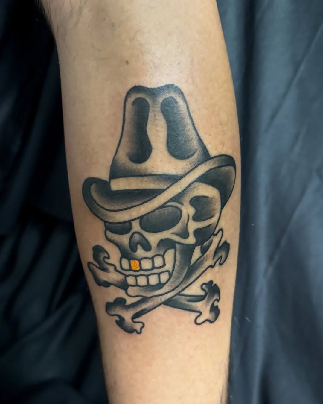 Skull with cowboy hat and crossbones American traditional tattoo on the forearm by @destineey_barton
