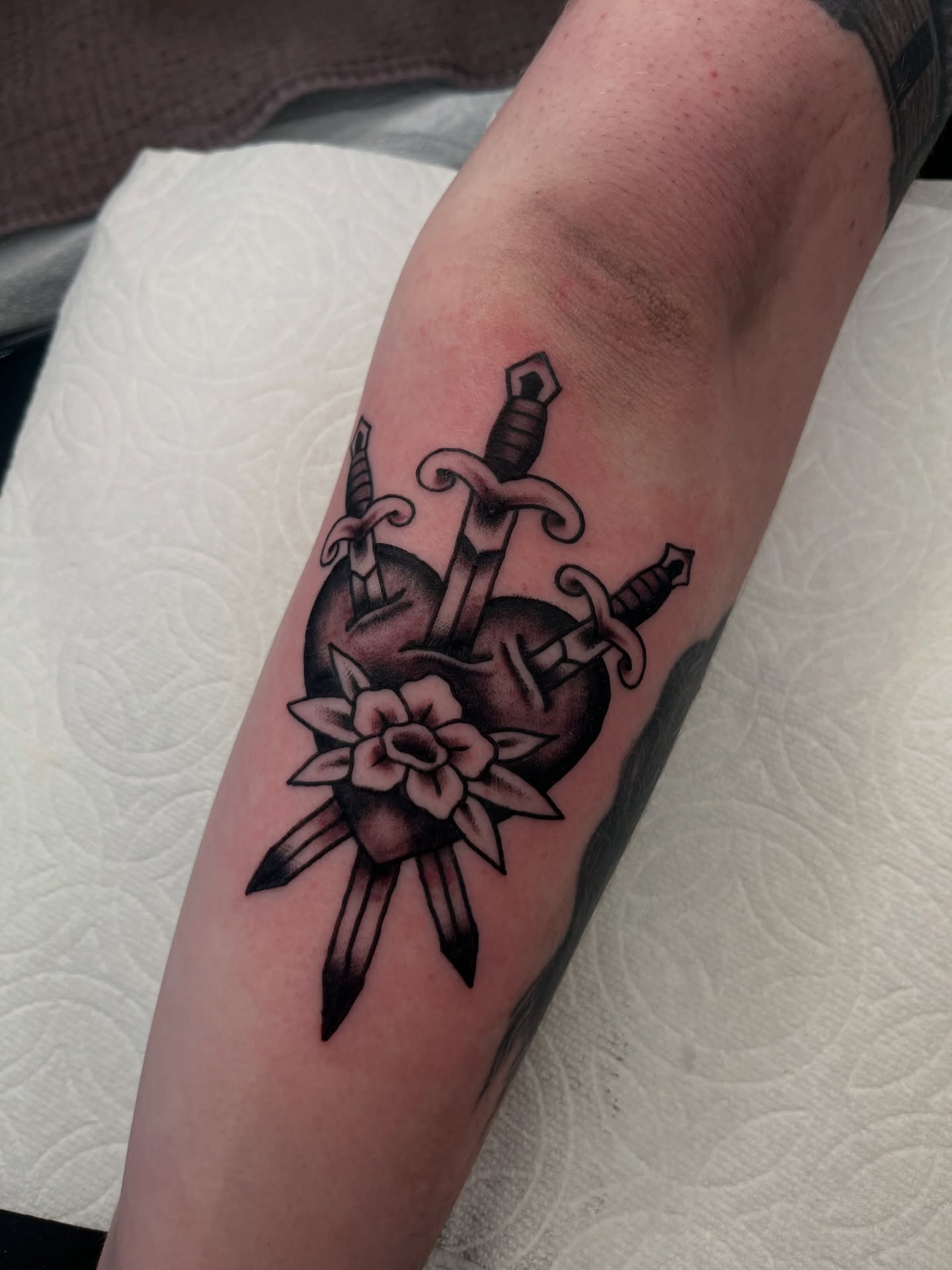 Sword and flowers American traditional tattoo on the forearm by Kehrmie Tattoos, Berkeley, California