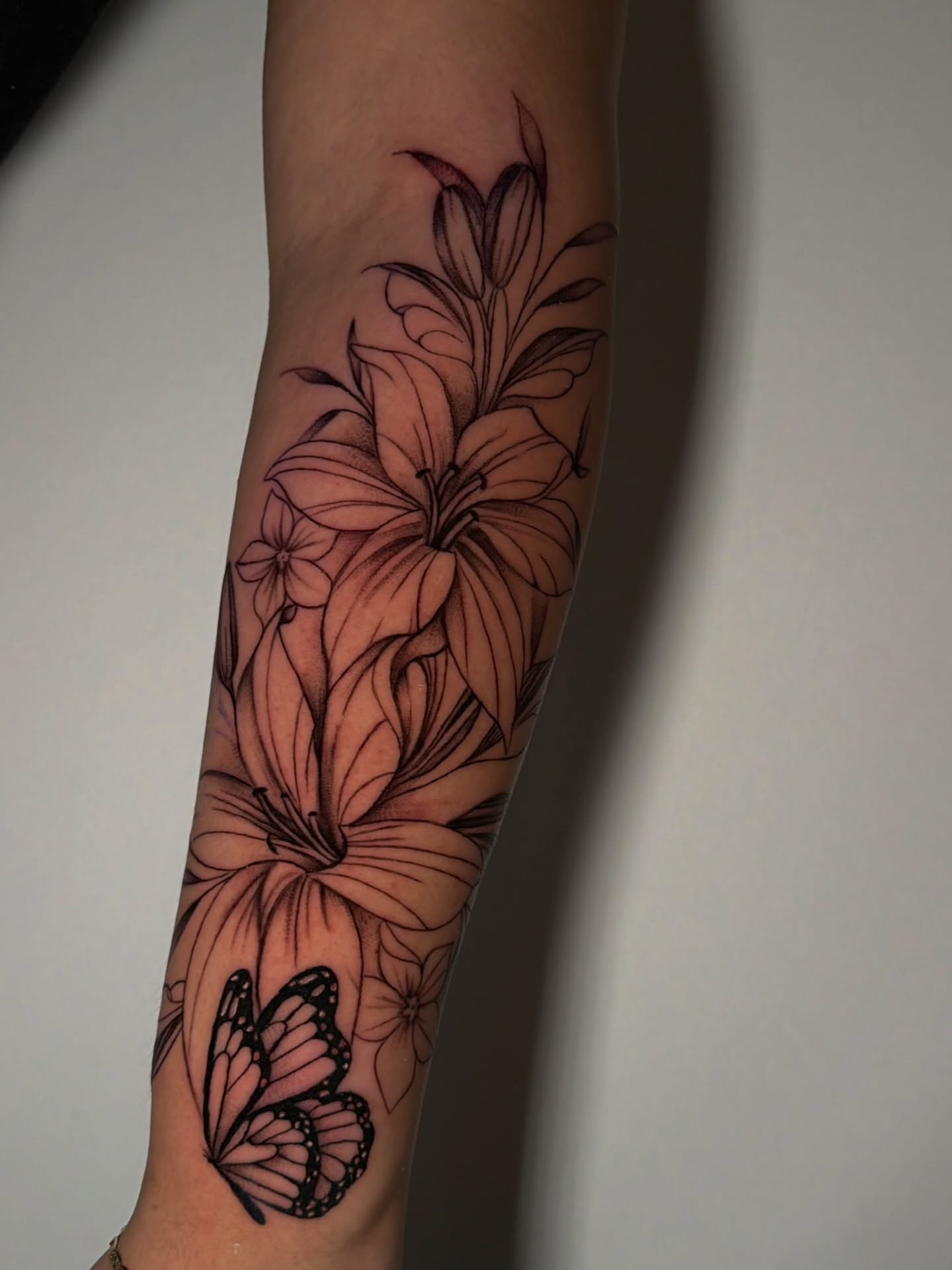 Lilies and butterfly black and grey tattoo on the forearm by ๐ธ๐๐๐.๐ฎ๐, Los Angeles, California