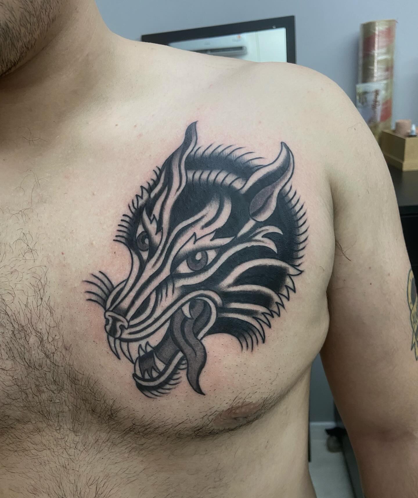 Wolf head black and grey tattoo on the chest by Lucas Naganuma