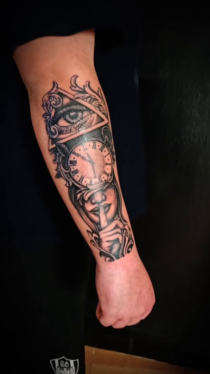 All-seeing eye with clock and face surrealism tattoo on the forearm by Juanma Martin