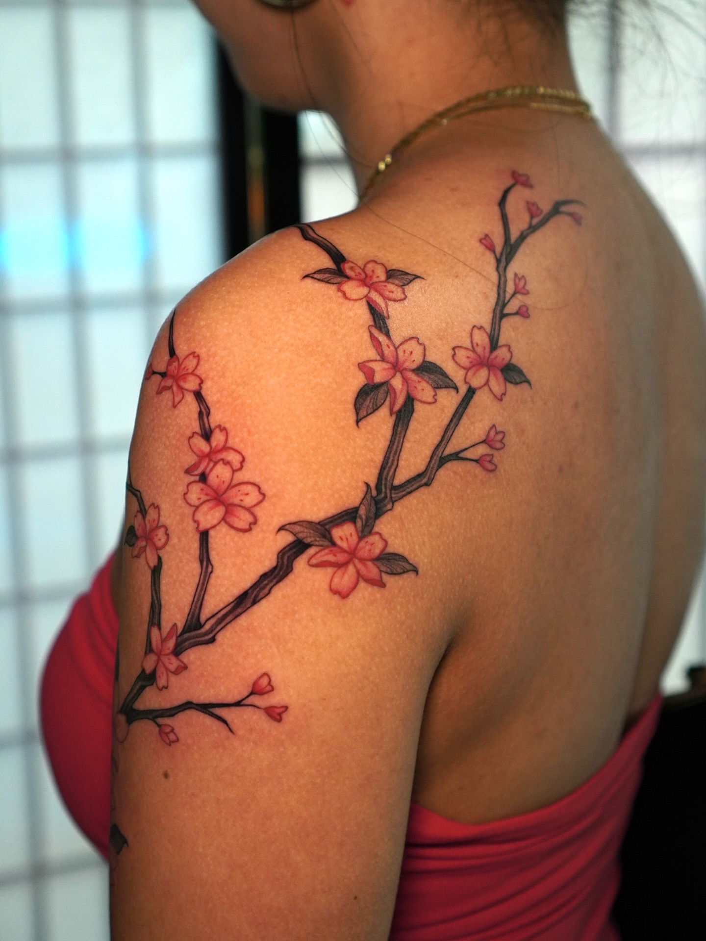 Cherry blossom branch realism tattoo on the shoulder by Carlos Abad