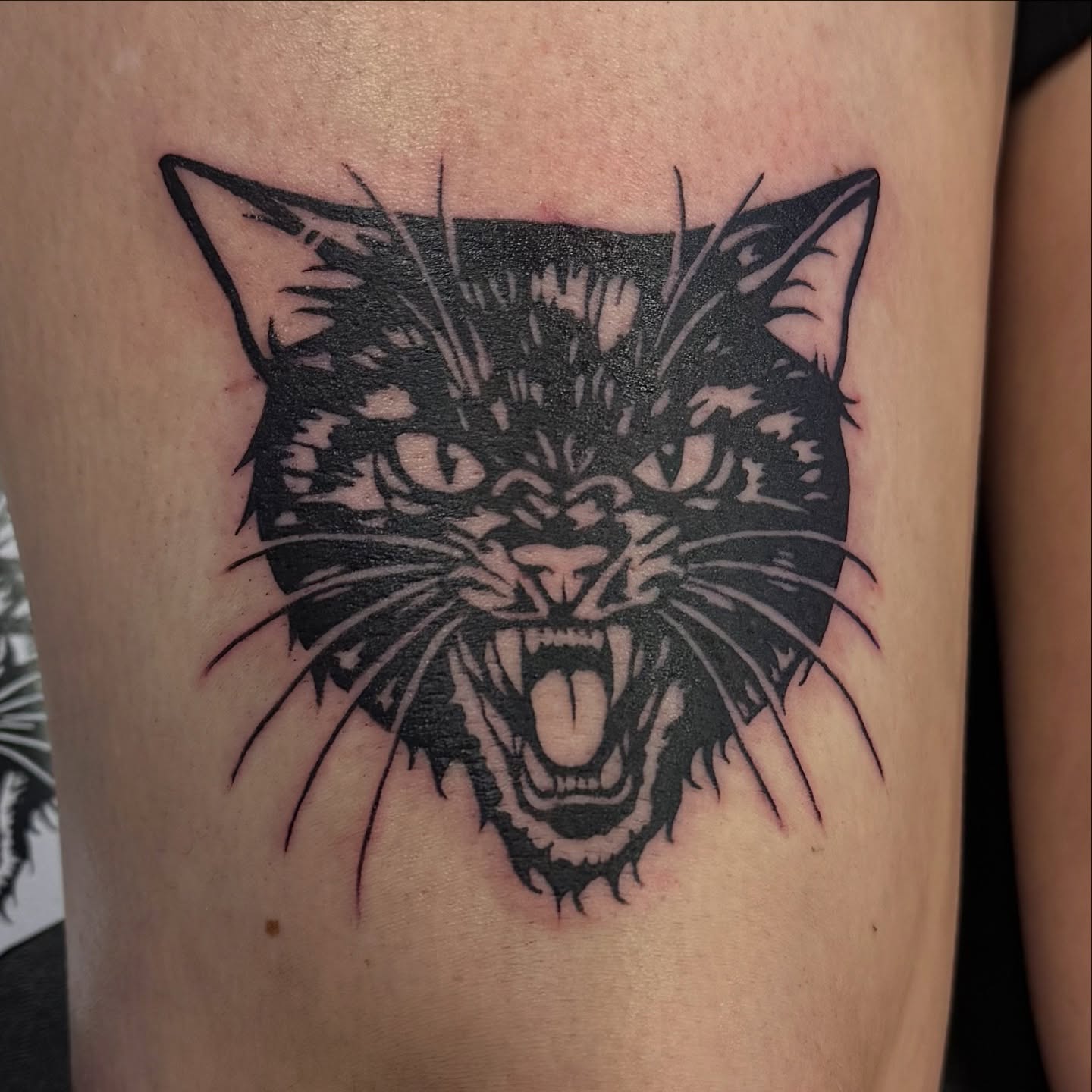 Cat black and grey tattoo on the thigh by Kat Bennett