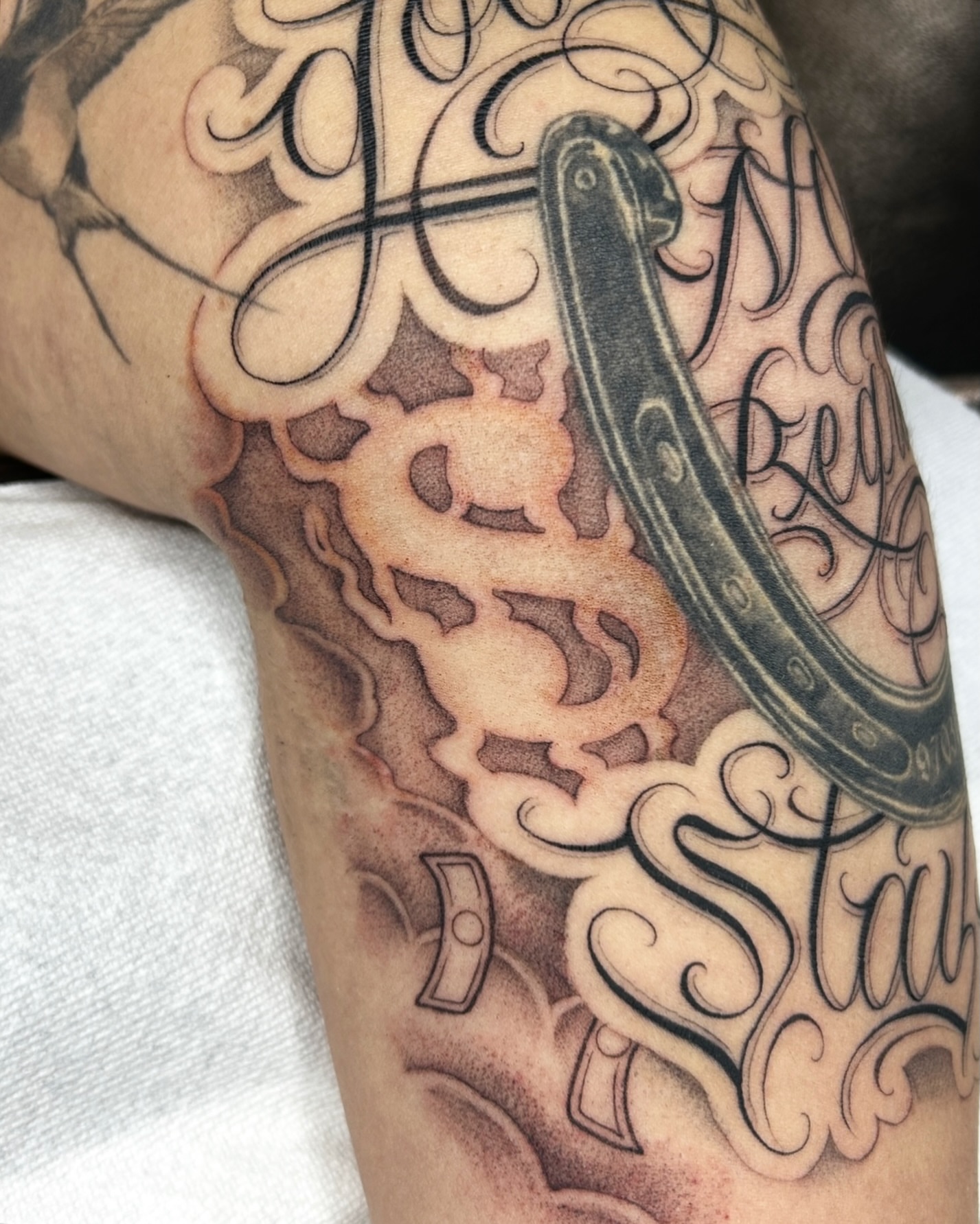 Horseshoe and script black and grey tattoo on the forearm by Joon 치카노레터링