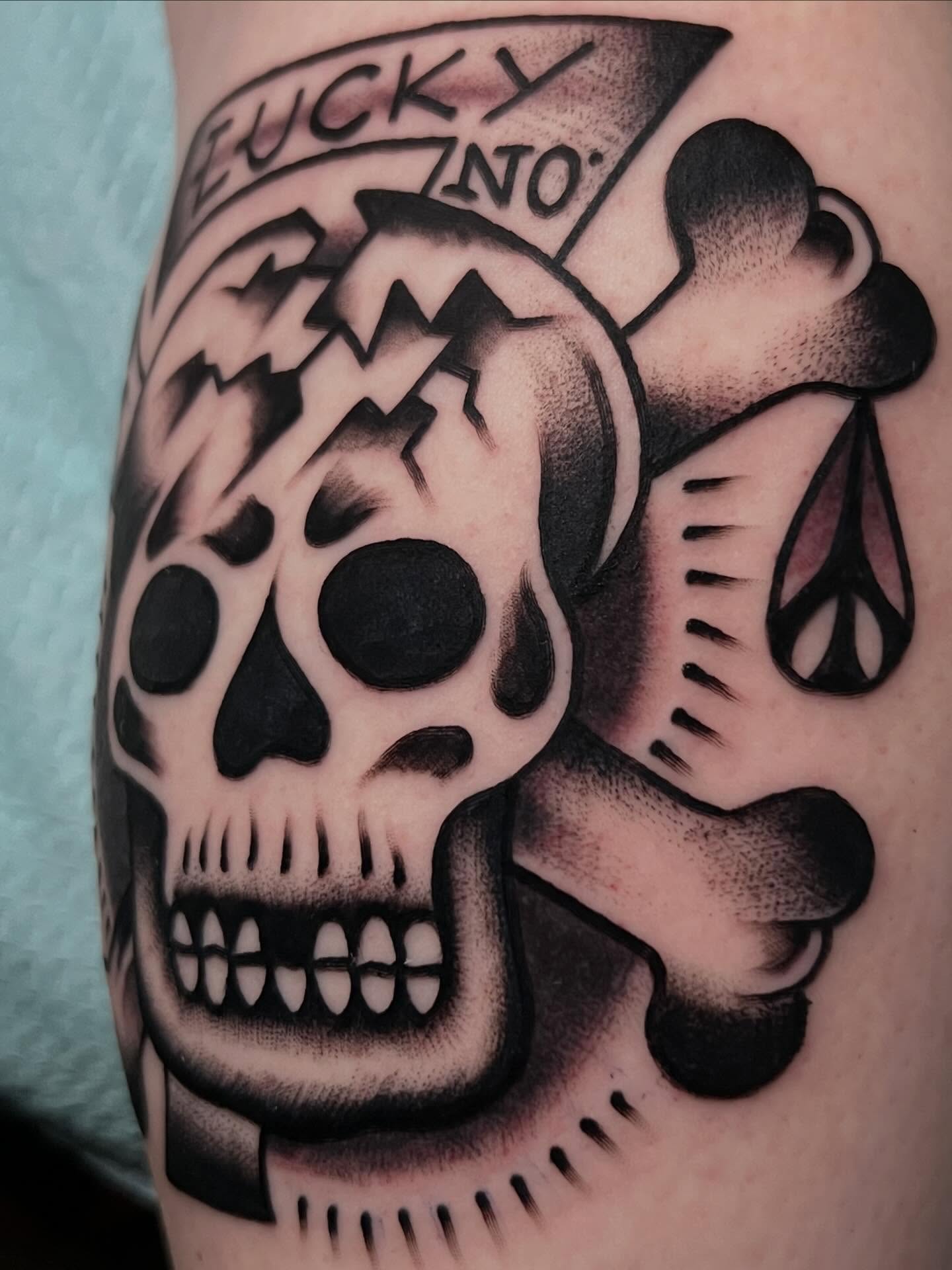 Skull and crossbones American traditional tattoo on the forearm by Charlie Campanella