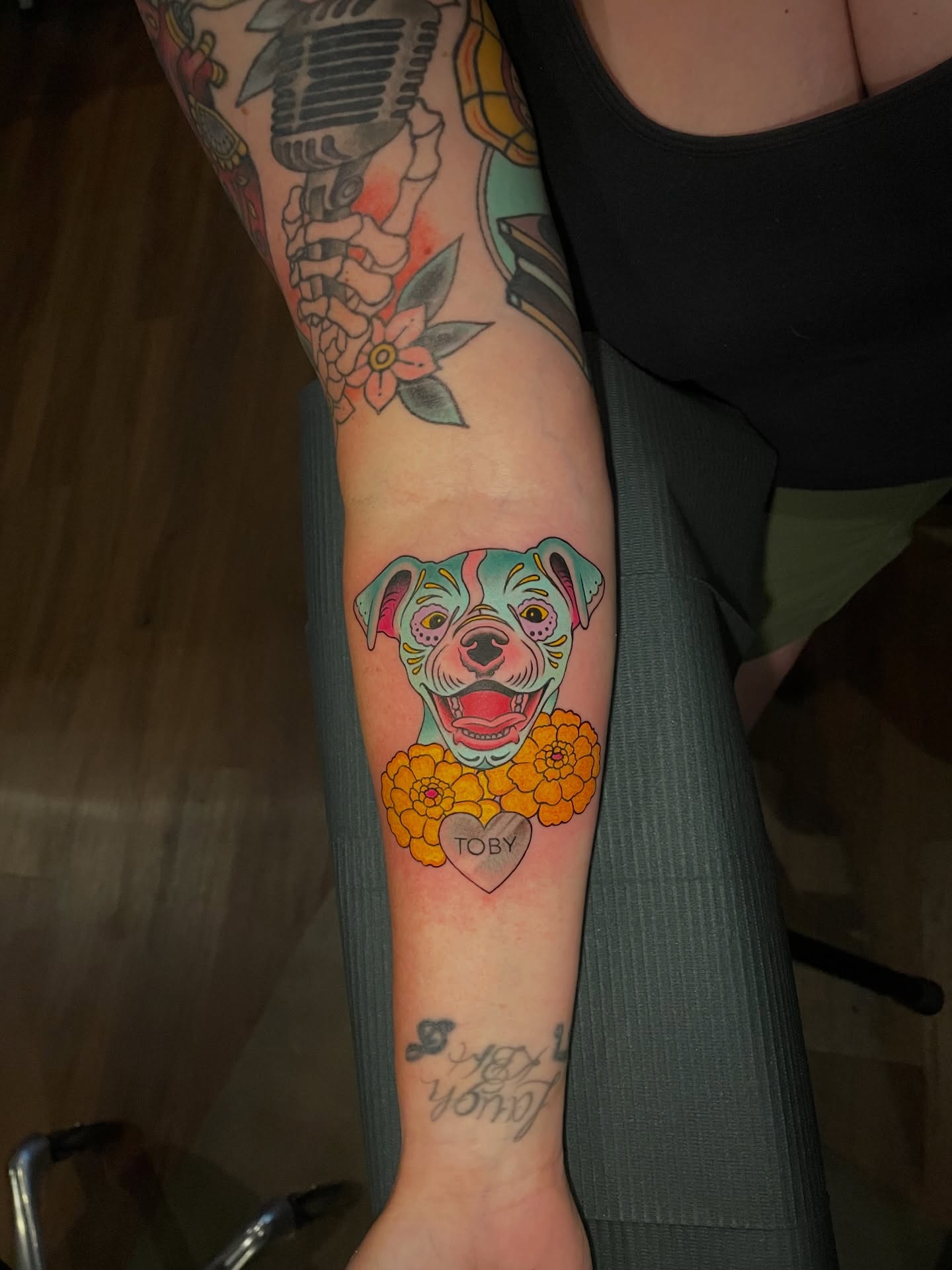 Dog with flowers new school tattoo on the forearm by Ｊｉｍ Ｓｙｌｖｉａ