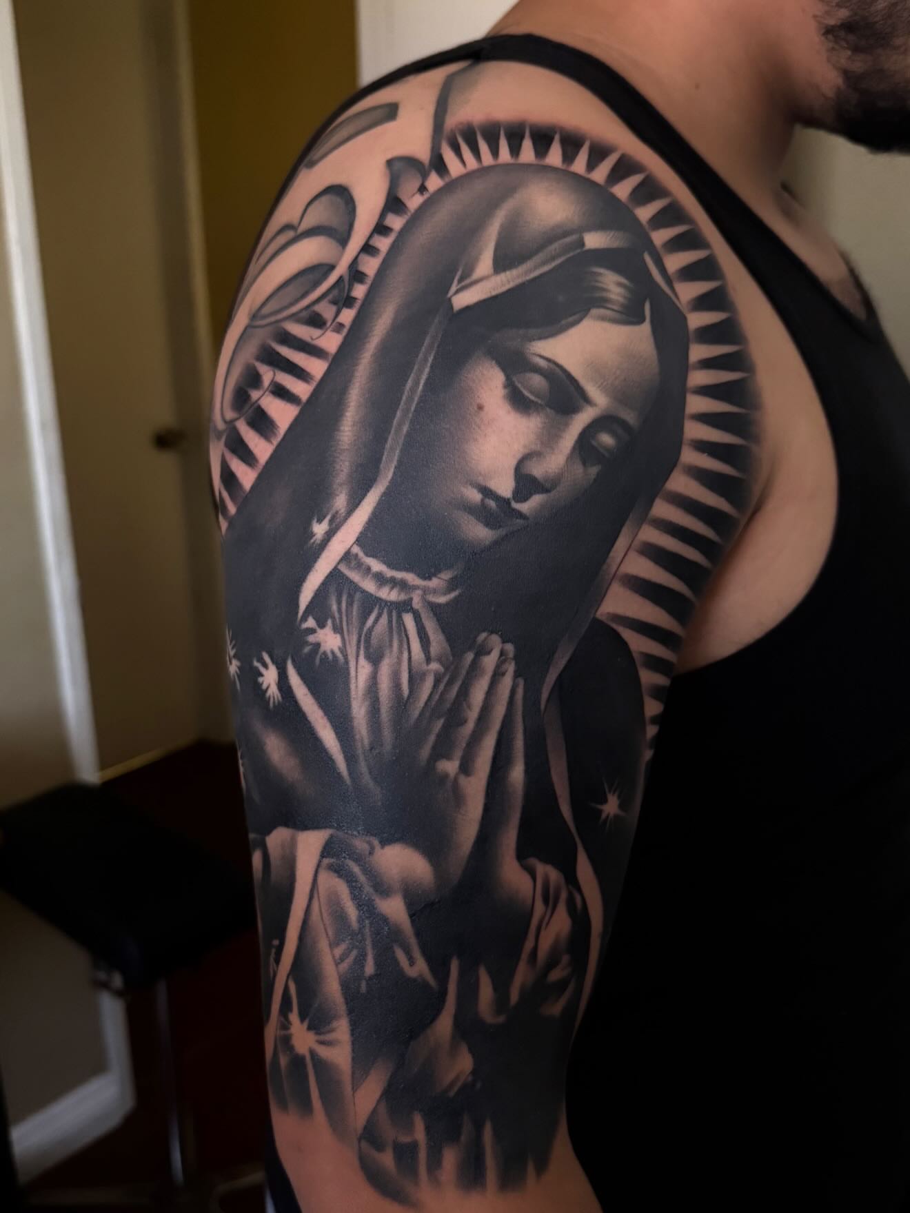 Religious figure praying realism tattoo on the upper arm by TattooBoyTattoos