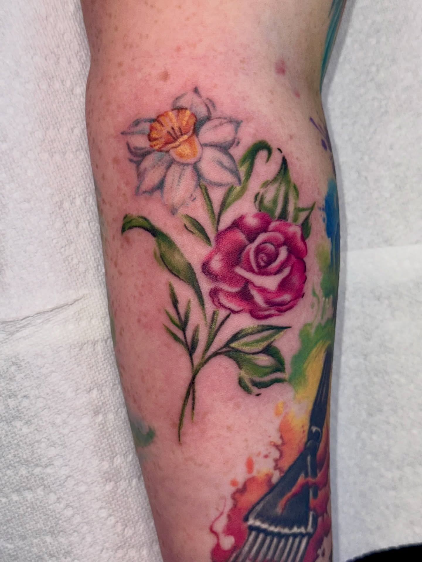 Daffodil and rose watercolor tattoo on the forearm by Caitlynn Austin