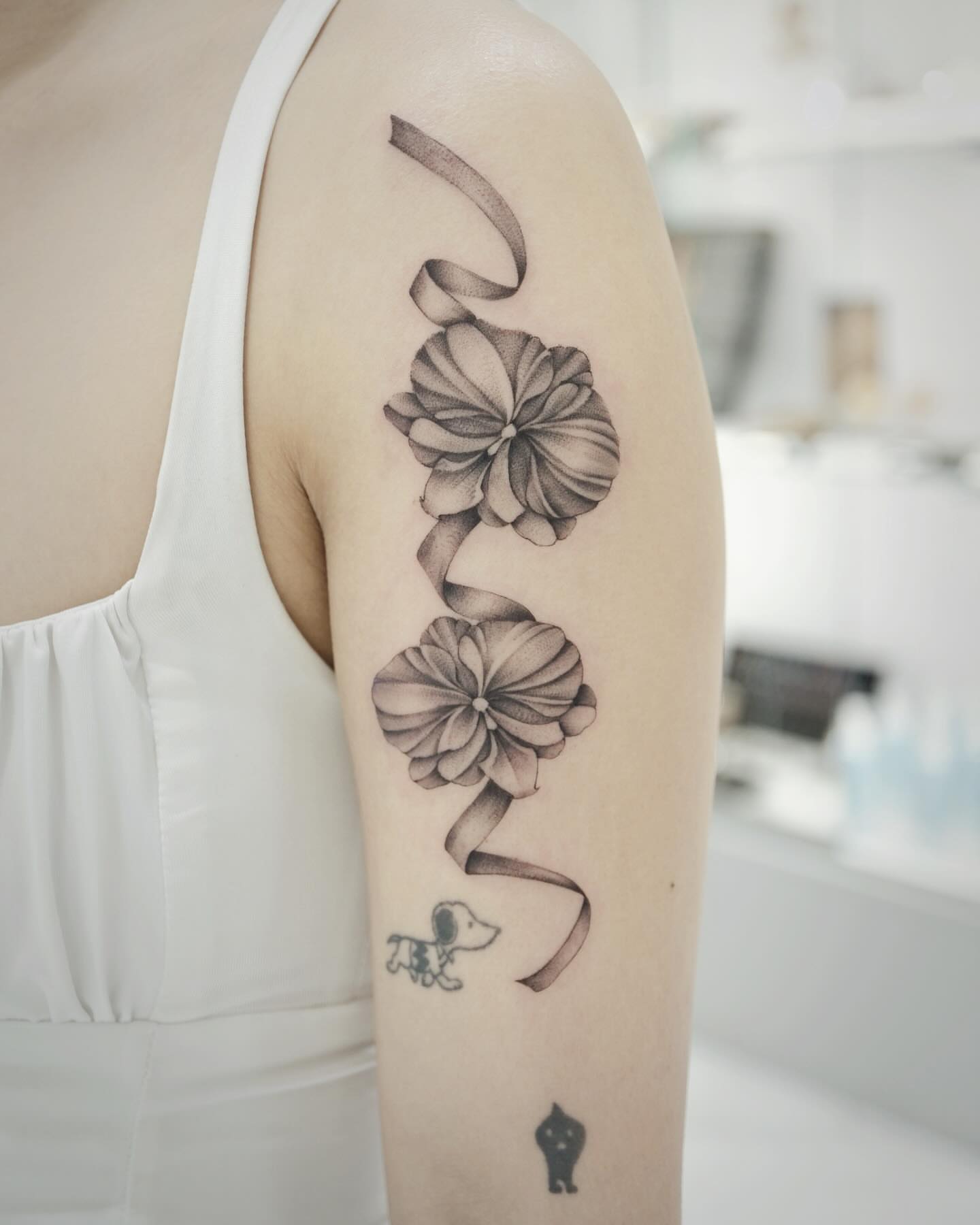 Flowers and ribbon dotwork tattoo on the upper arm by Raytattooist