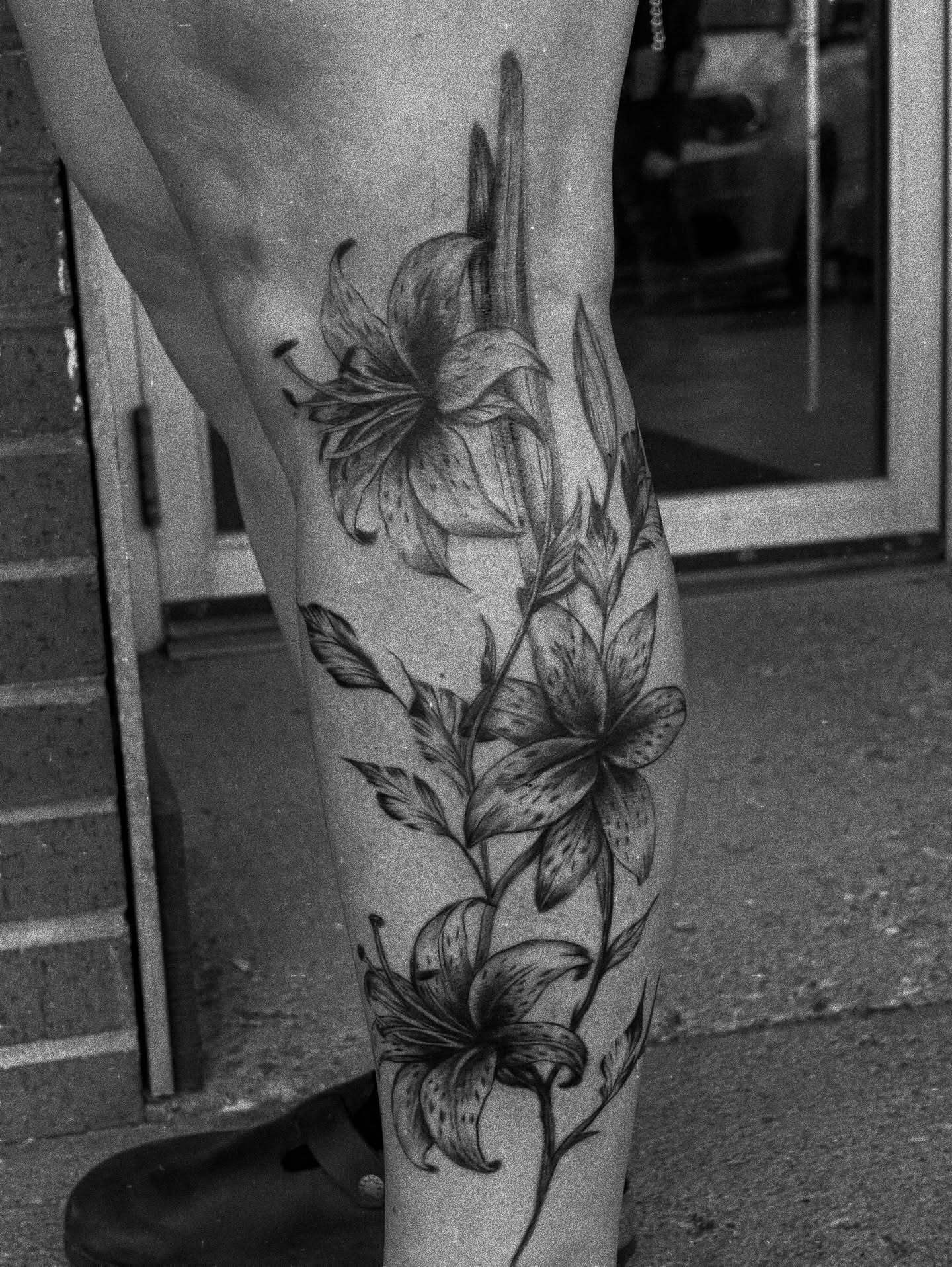 Lilies realism tattoo on the calf by ⚜️Embodied Tattoo⚜️, Columbus, Ohio