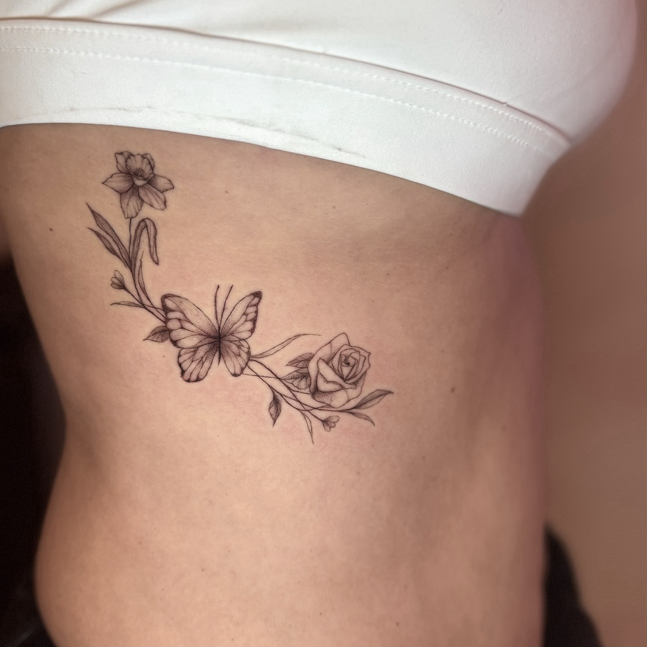 Butterfly and flowers black and grey tattoo on the ribs by fine line tattoo artist▪️Austin TX