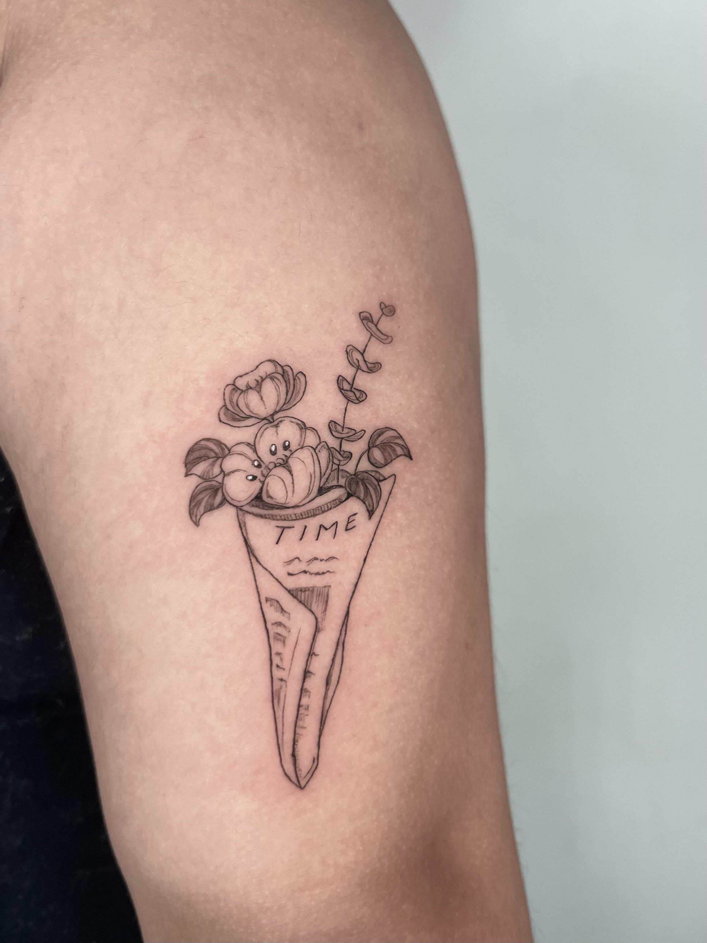 Time cone with flowers black and grey tattoo on the upper arm by Sierra Skye