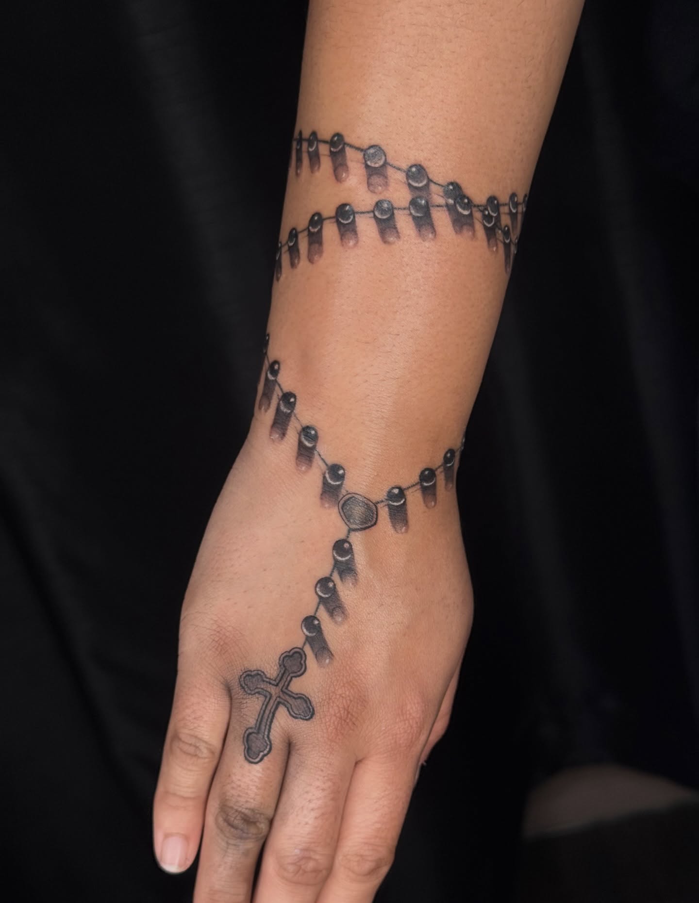 Rosary black and grey tattoo on the hand by North County Sd