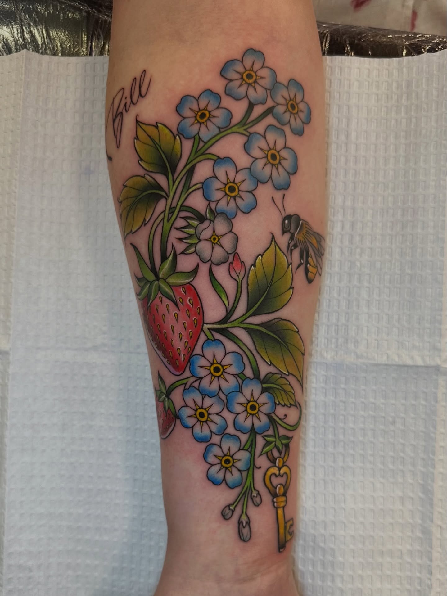 Strawberries, flowers, bee, key American traditional tattoo on the forearm by Sam AlpineInk