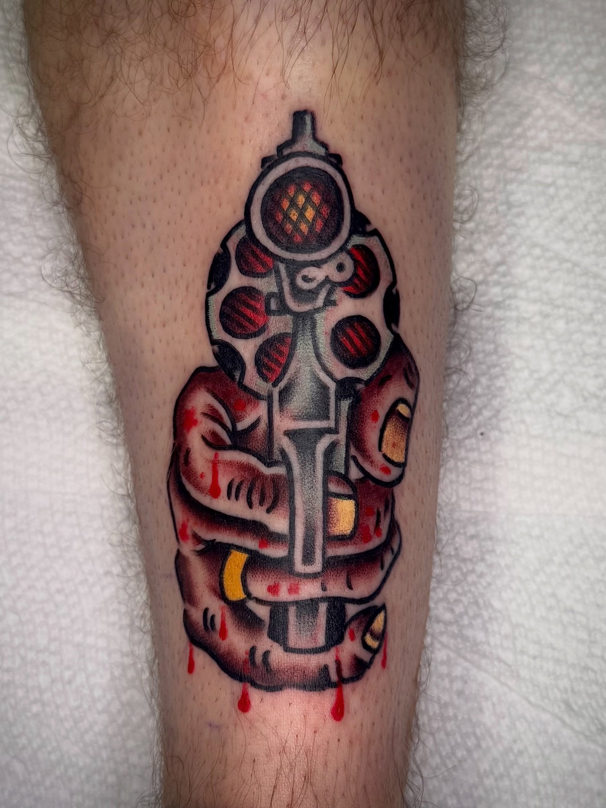 Gun with blood American traditional tattoo on the forearm by Andrew Silva